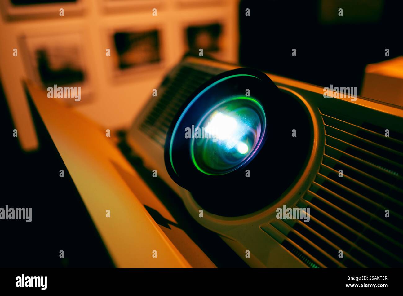 Nahaufnahme einer leuchtenden Projektorlinse, die blaues Licht in einem schwach beleuchteten Raum ausstrahlt. Die filmische Atmosphäre und die scharfe Fokussierung heben die Details des hervor Stockfoto