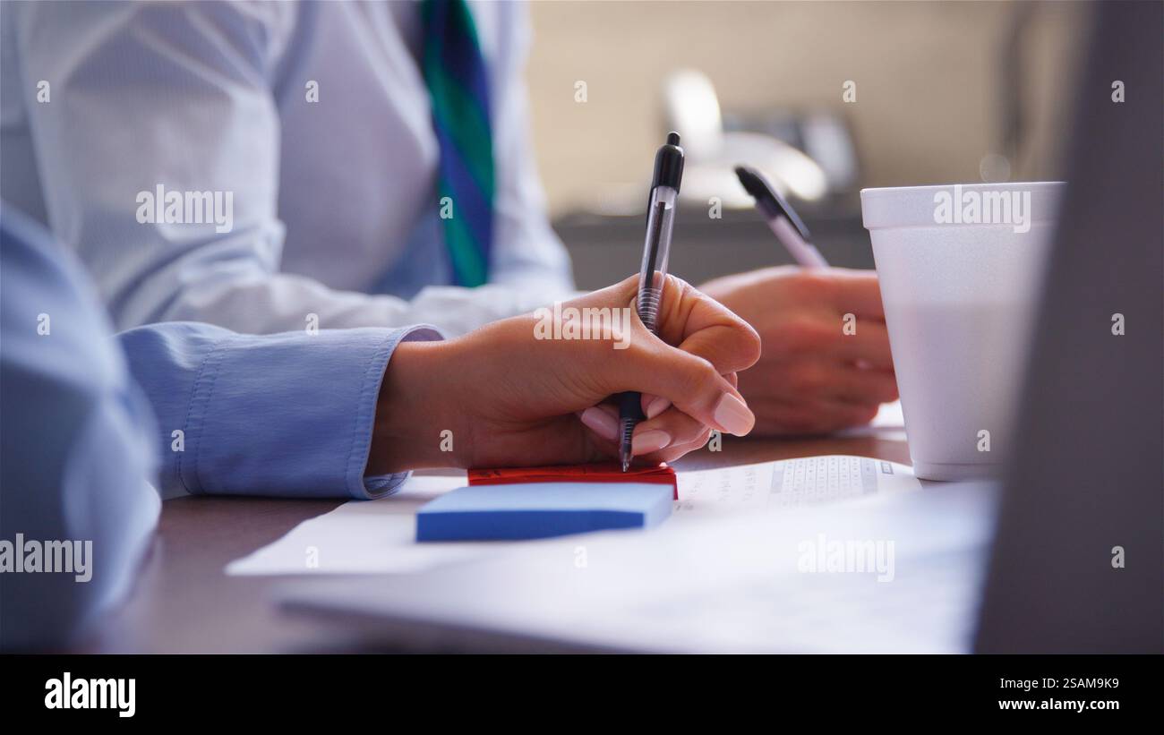 Nahaufnahme Der Besprechung Des Business-Teams, Die Sich Um Den Tisch Im Büro Herum Mit Getränketassen Zusammensetzt, Um Notizen Zu Machen Stockfoto