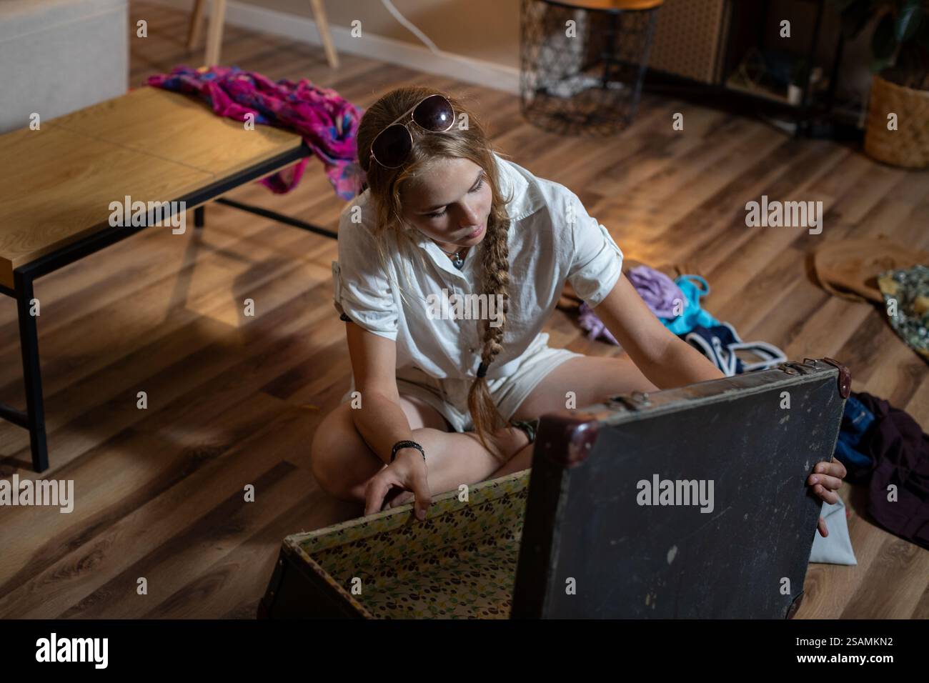 Erleben Sie das aufregende Erlebnis, Schätze aus einer Vintage-Truhe in einem gemütlichen Zimmer auszupacken Stockfoto