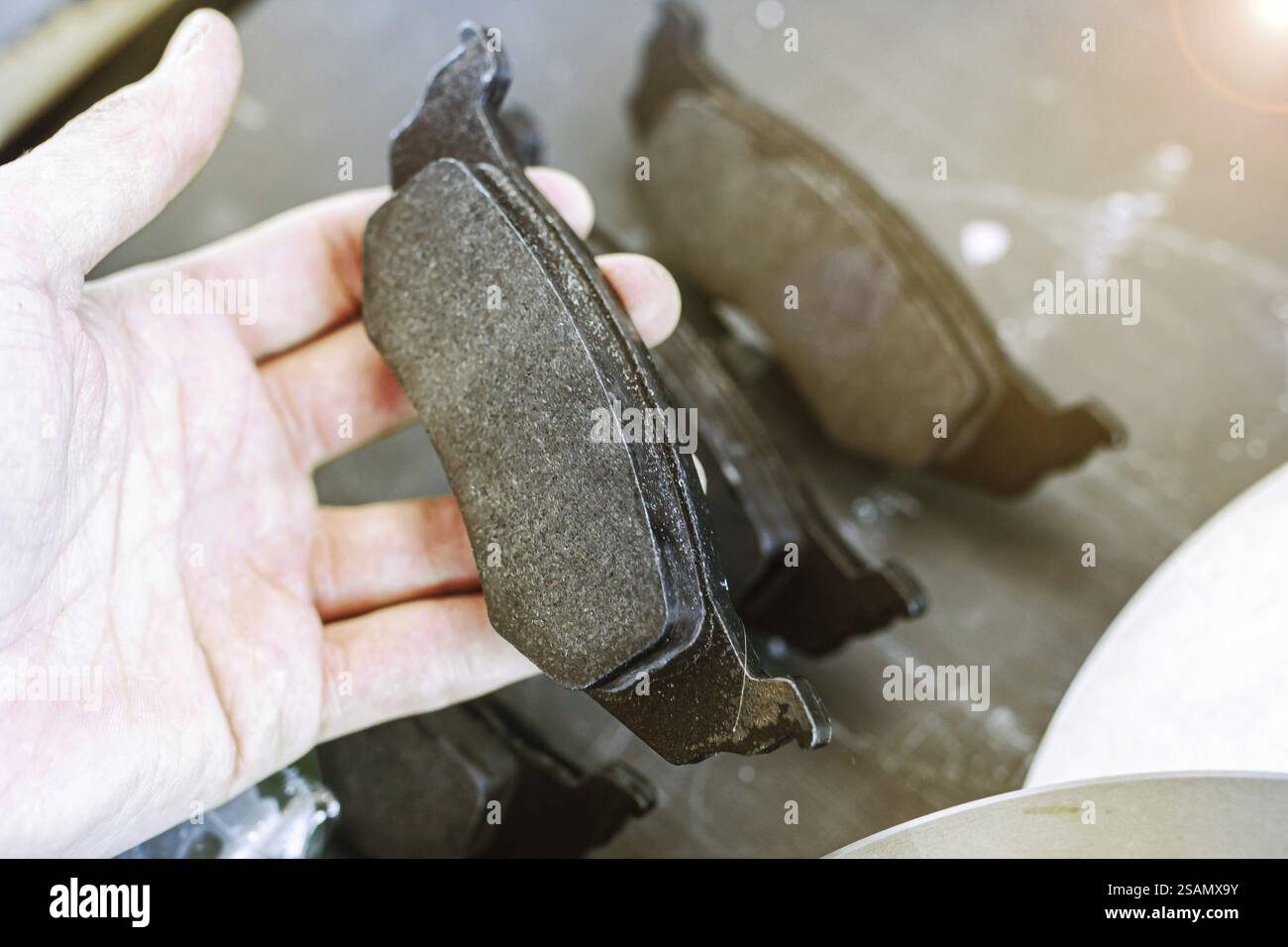 Eine Person hält einen Bremsbelag vor einem Hintergrund ähnlicher Beläge Stockfoto