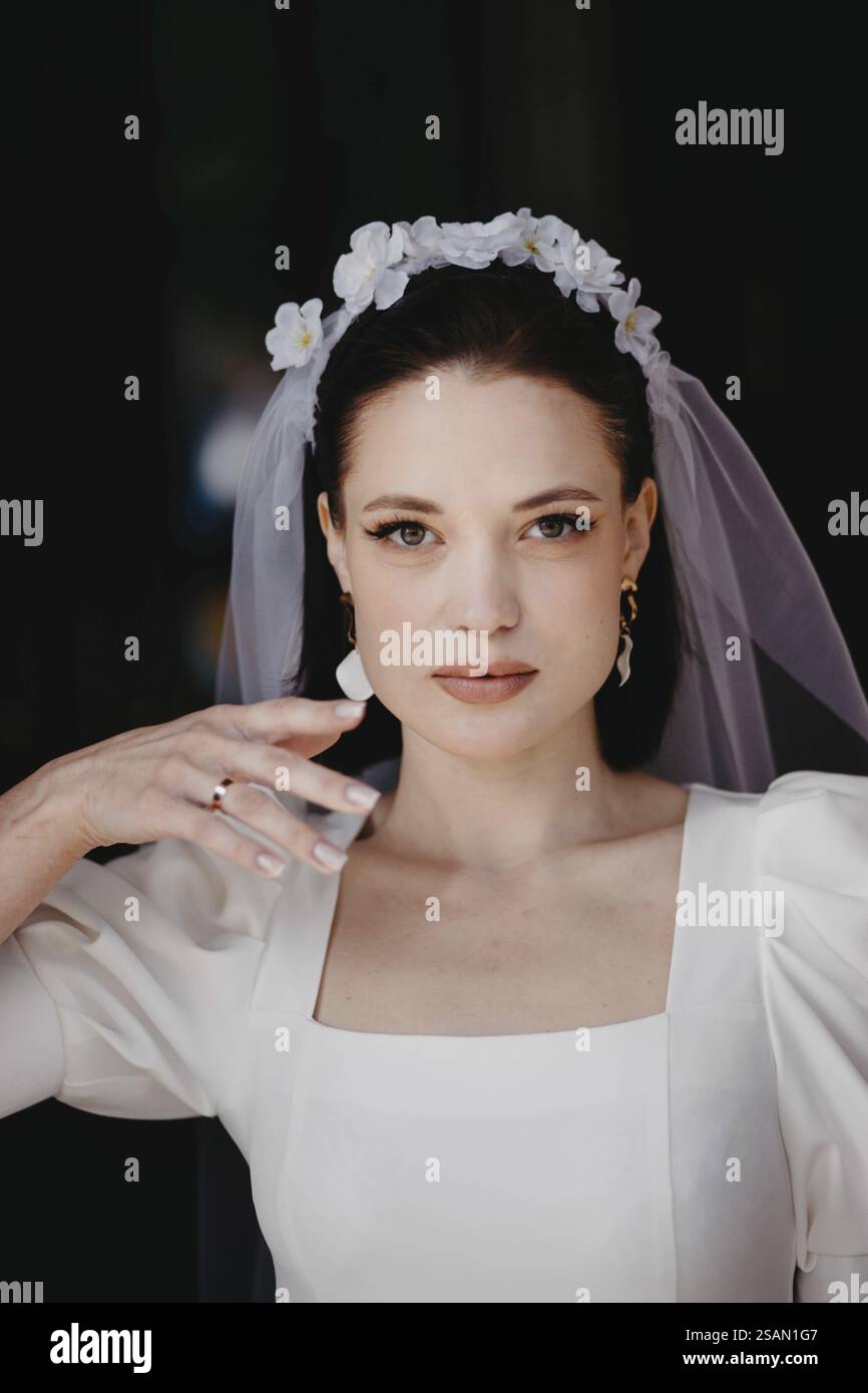 Nahaufnahme eines Porträts einer Frau in Brautkleider, mit Schleier und floralem Kopfschmuck, der ruhig aussieht Stockfoto