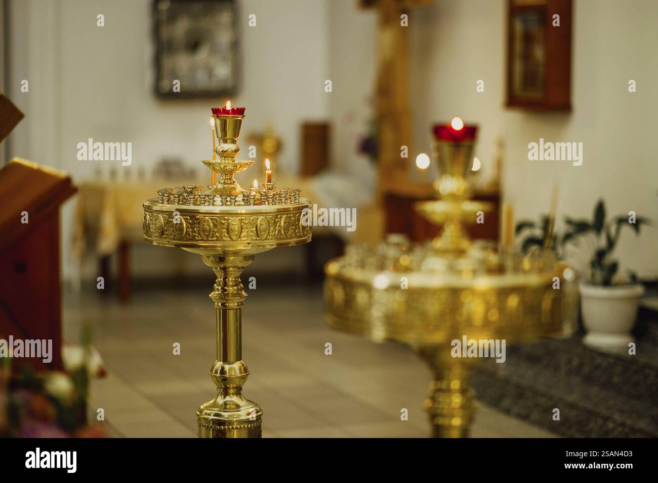 Goldener Kerzenhalter mit beleuchteten Kerzen in kirchlicher Umgebung, die das religiöse Ambiente hervorheben Stockfoto