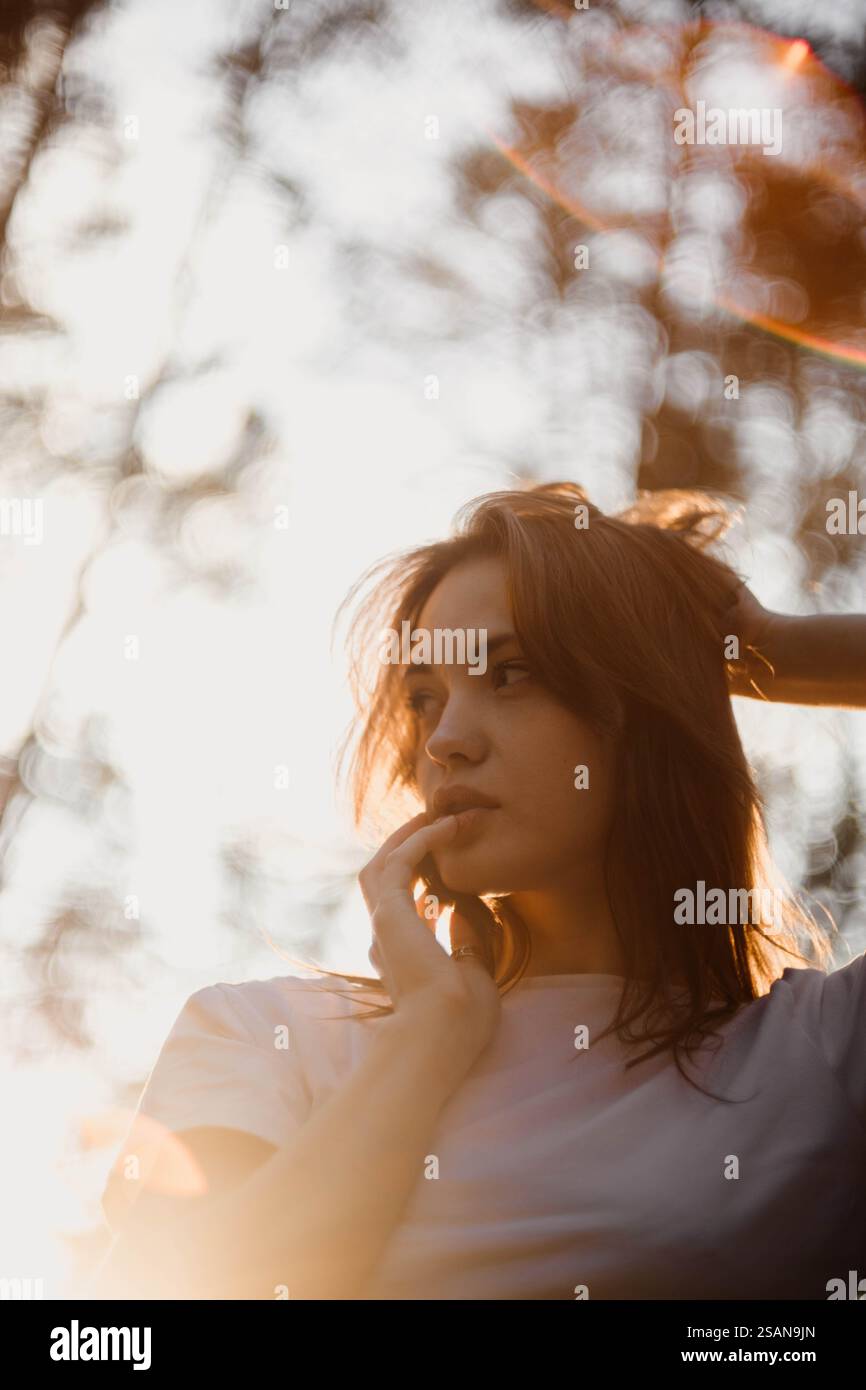 Frau im Denken, beleuchtet von sanftem Sonnenlicht in einer Waldumgebung Stockfoto