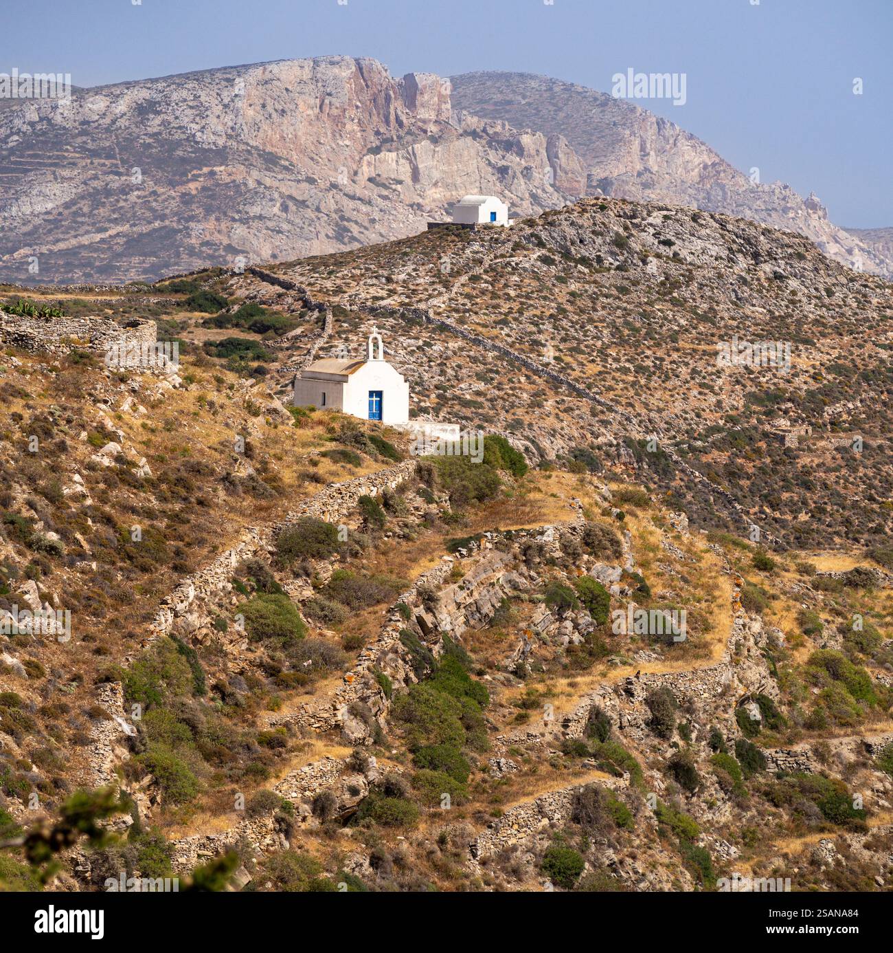 Abgelegene Gotteshäuser: Zwei kleine Kirchen auf den trockenen Terrassenhügeln nahe dem nördlichen Ende der Insel Folegandros. Stockfoto
