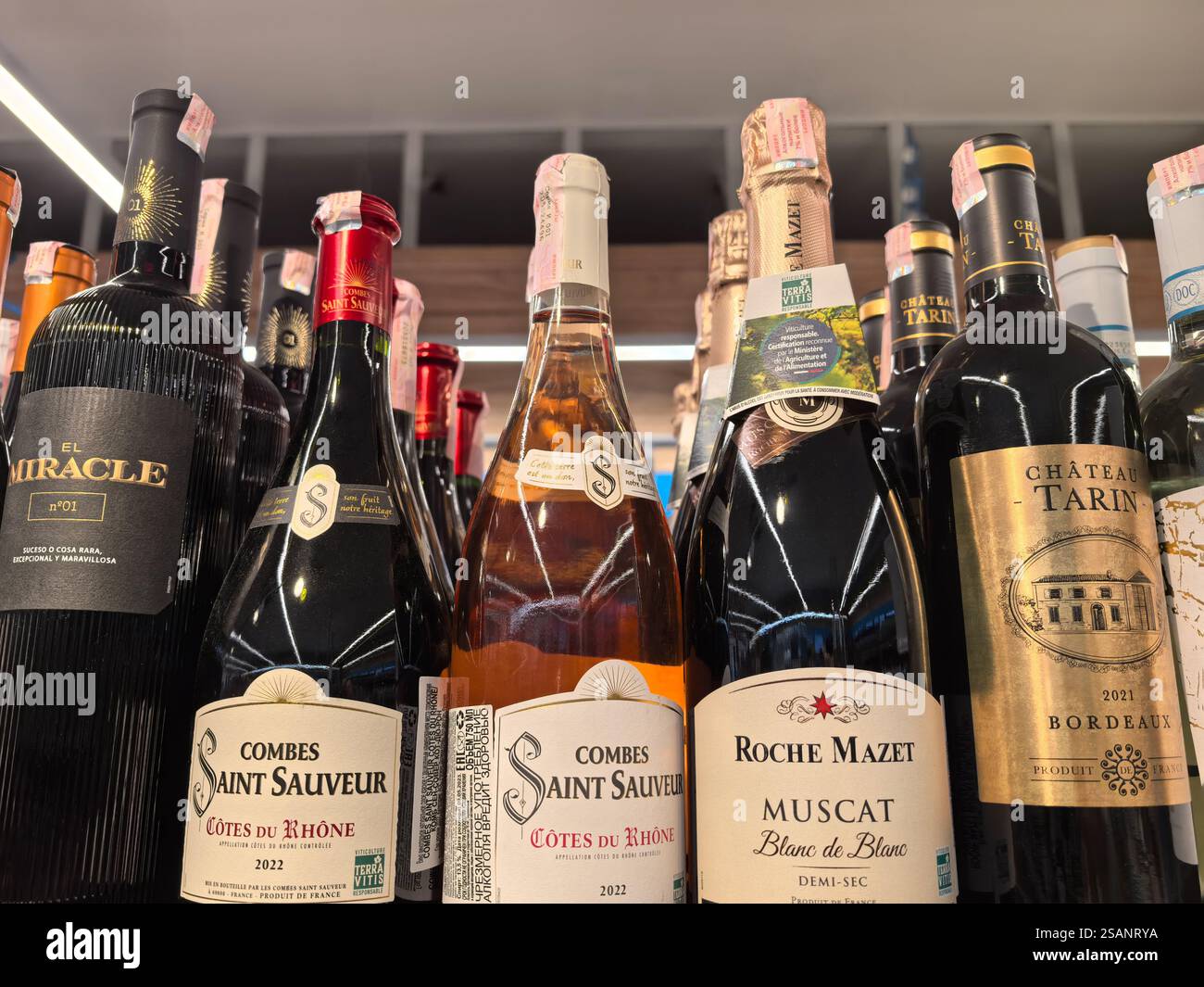 Bobruisk, Weißrussland - 17. Januar 2025: Reihen sorgfältig ausgewählter Weinflaschen säumen die Regale in einer gemütlichen Boutique. Die warme Umgebungsbeleuchtung verbessert sich Stockfoto