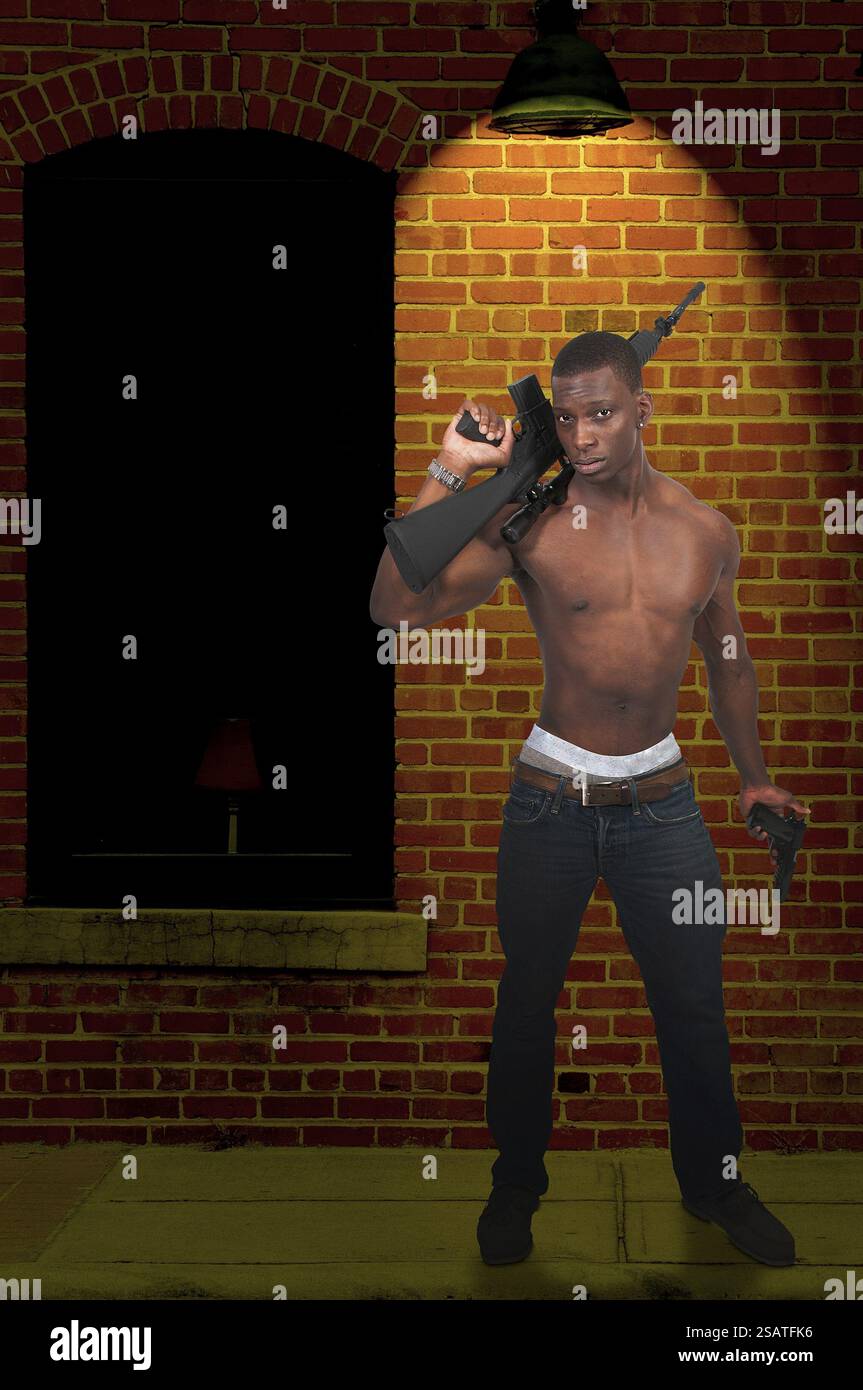 Junger Mann mit automatischem Sturmgewehr und Pistole Stockfoto