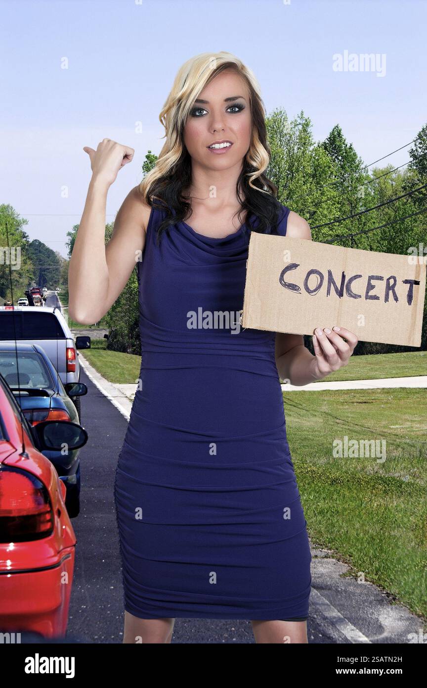 Eine schöne Frau mit einem Schild Trampen zu einem Konzert Stockfoto
