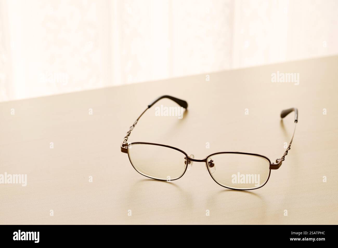 Augenbrille auf einem Holztisch am hellen Fenster Stockfoto