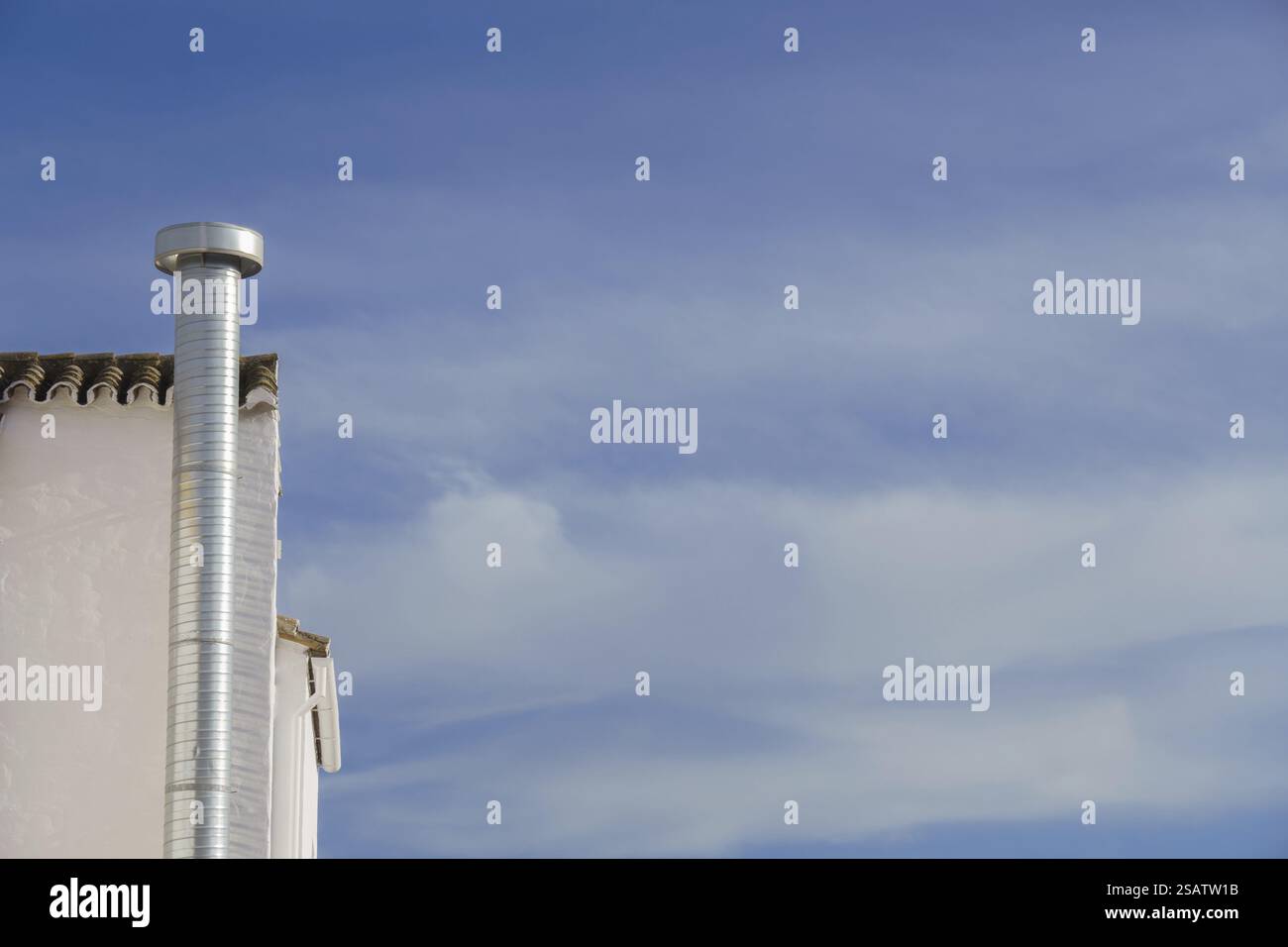 Metallschornstein an der Fassade eines Gebäudes mit bewölktem Himmel im Hintergrund und Kopierraum Stockfoto