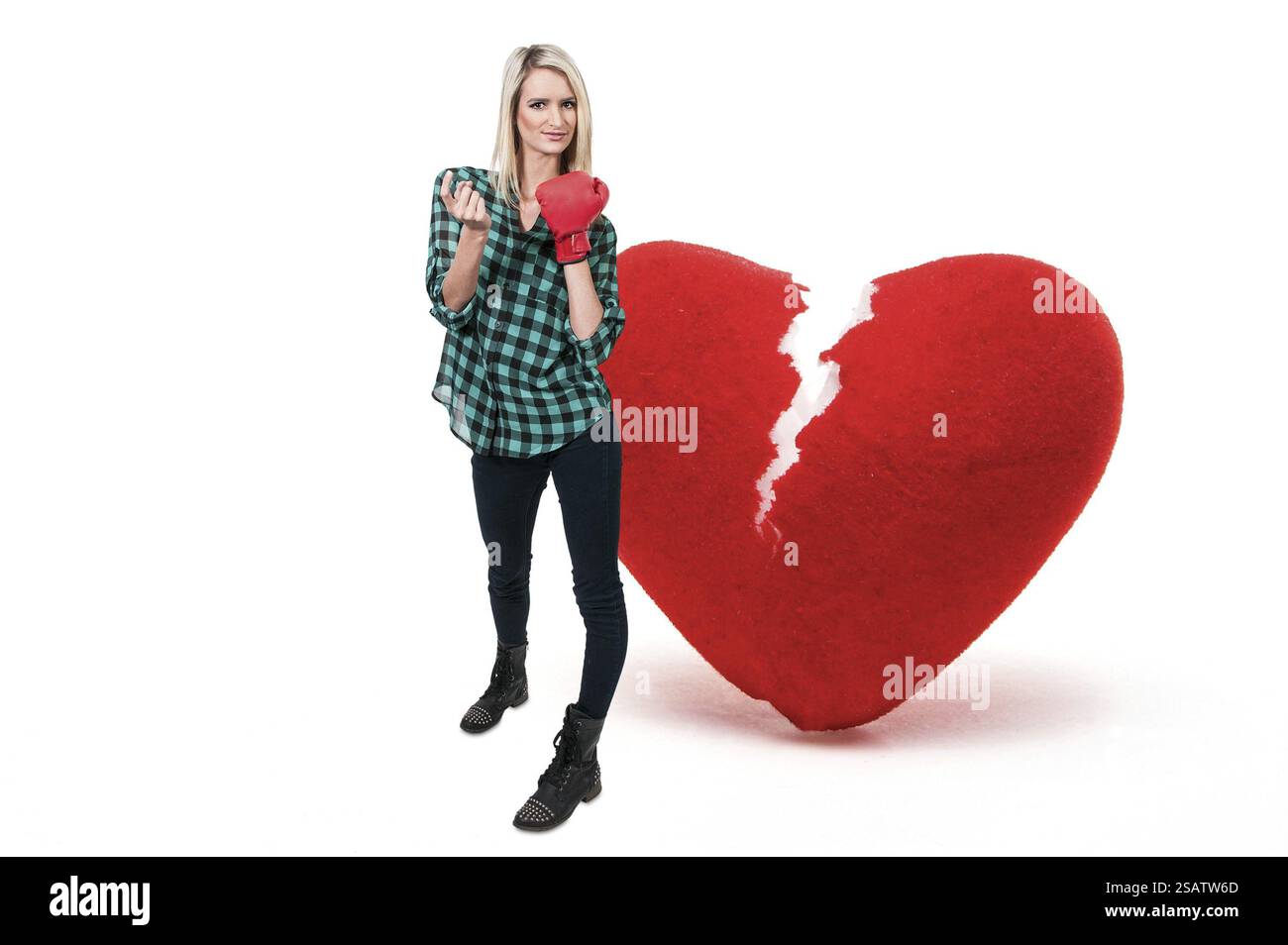 Schöne Frau trägt einen Boxhandschuh vor ein gebrochenes Herz - Herzensbrecher Stockfoto