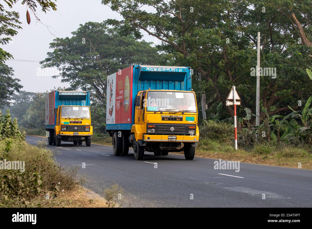 Zwei schwere Lastwagen fahren entlang der Straße in Chalanbil, Bezirk Pabna, Bangladesch. Stockfoto