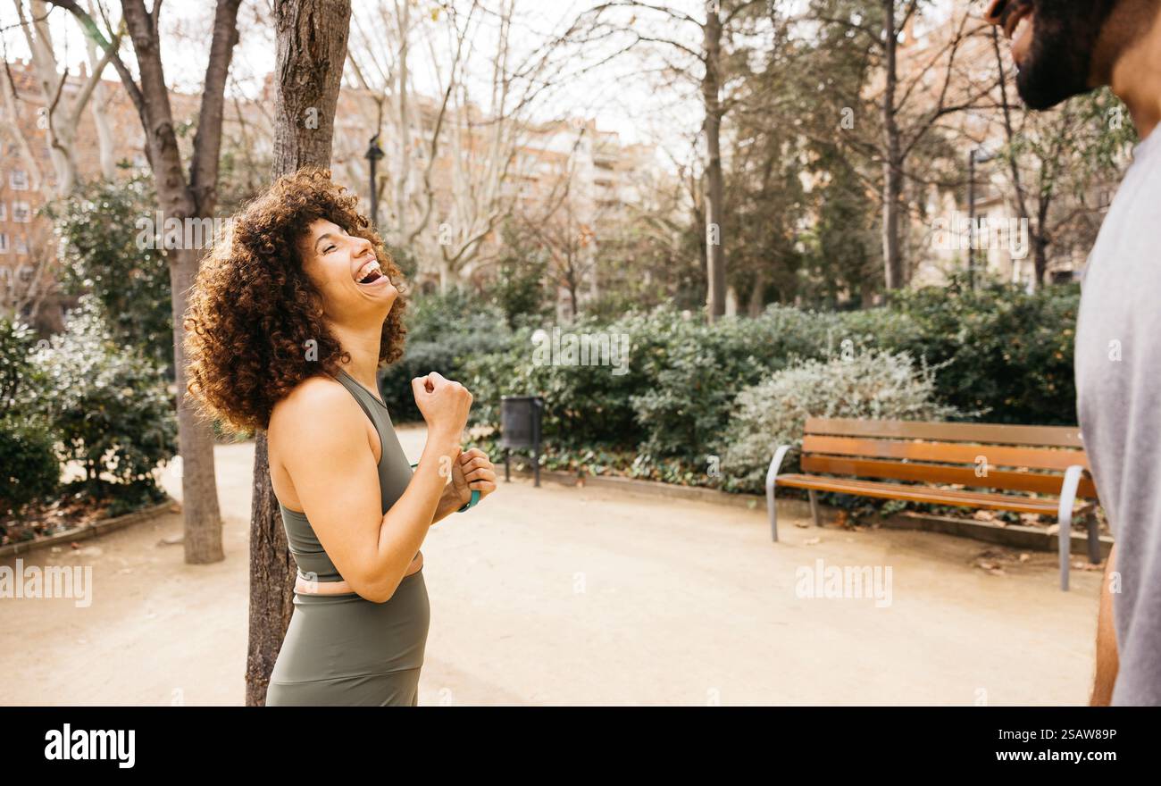 Glückliche sportliche Frau, die mit einem Partner im Park im Freien ein Training macht. Zeigt Fitness, Positivität und soziale Interaktion in einem Stadtpark. Stockfoto