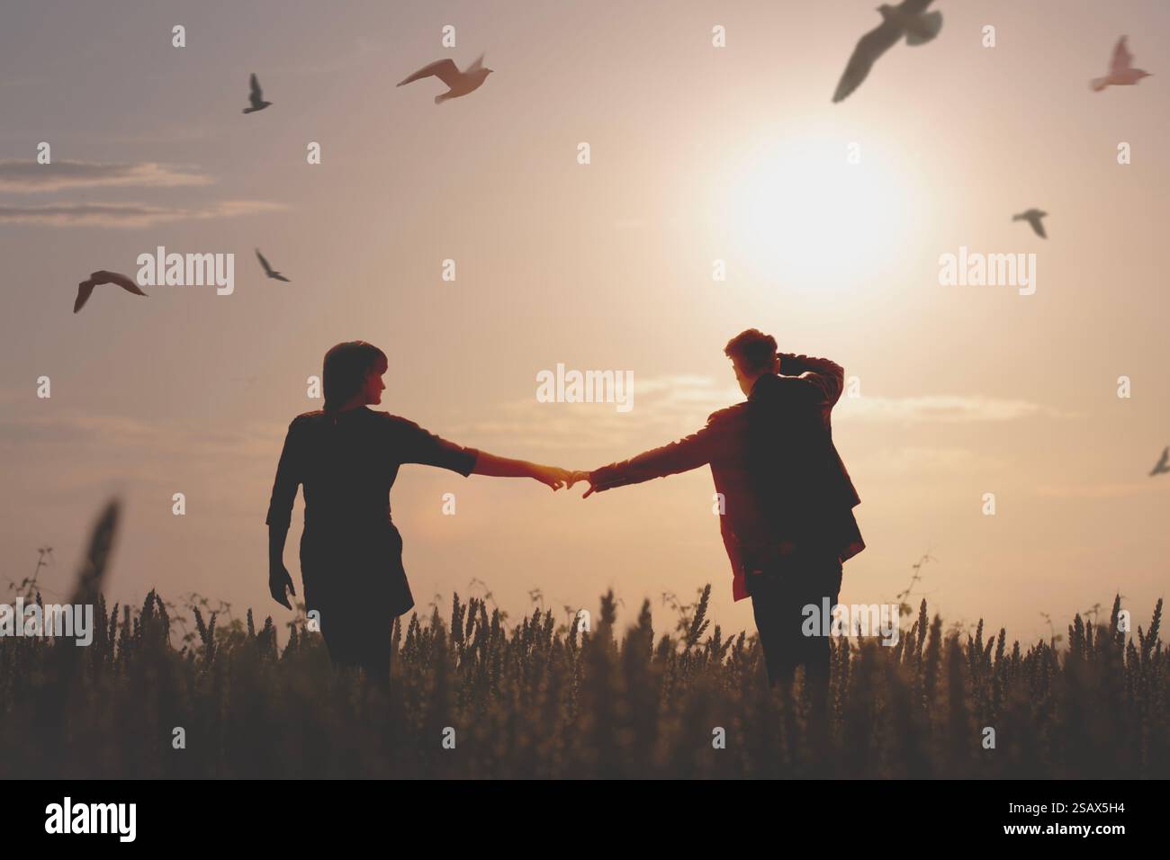 Ein Paar spaziert durch die Wiesen, umgeben von Vögeln im Flug Stockfoto