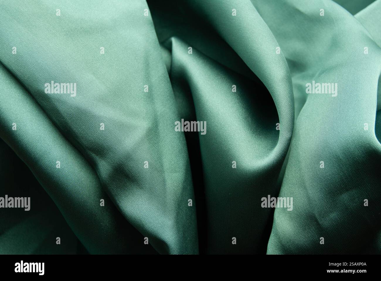 Weicher, pastellgrüner Seidenstoff mit zarten Falten und einer glatten Textur. Stockfoto