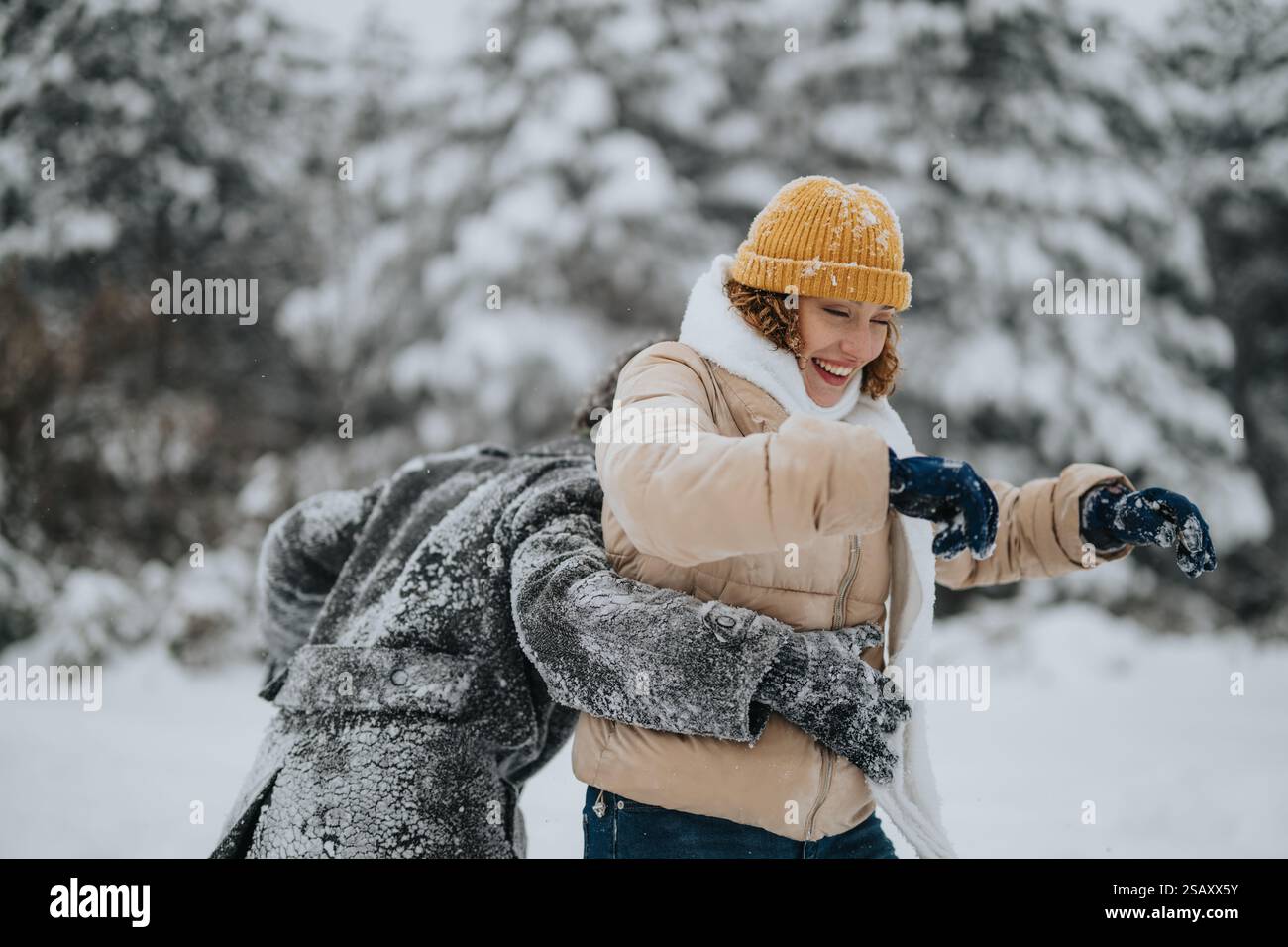 Fröhliche Freunde spielen in verschneiten Winterlandschaften, umgeben von Bäumen Stockfoto
