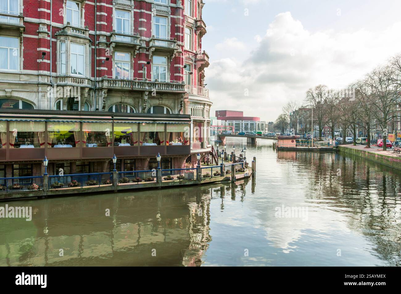 Amsterdamer Stadtbild mit einem roten Backsteingebäude entlang eines geschwungenen Kanals, Niederlande, Europa. Stockfoto