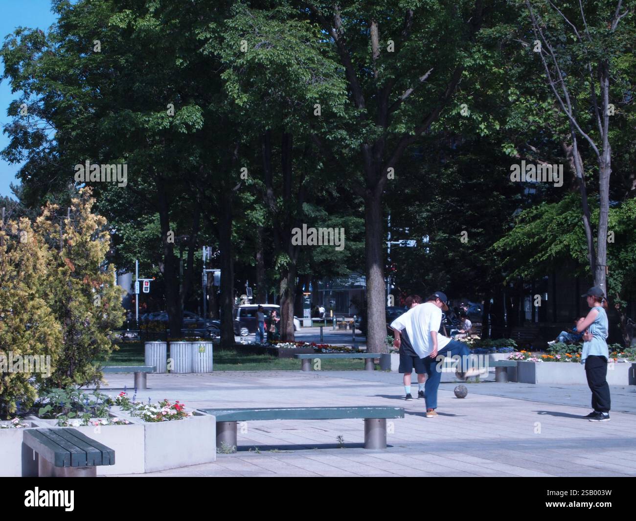 Drei Leute spielen im Sommer mit einem Ball in einem Park. OLYMPUS DIGITALKAMERA Stockfoto