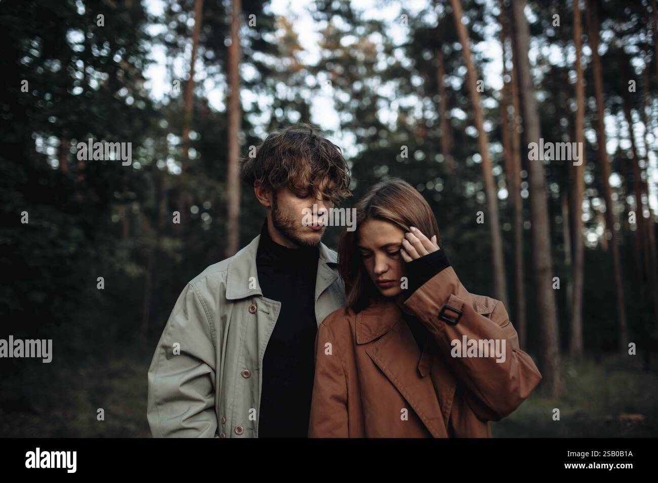 Ein Paar in einem intimen und nachdenklichen Moment im Wald, in Herbstmänteln Stockfoto