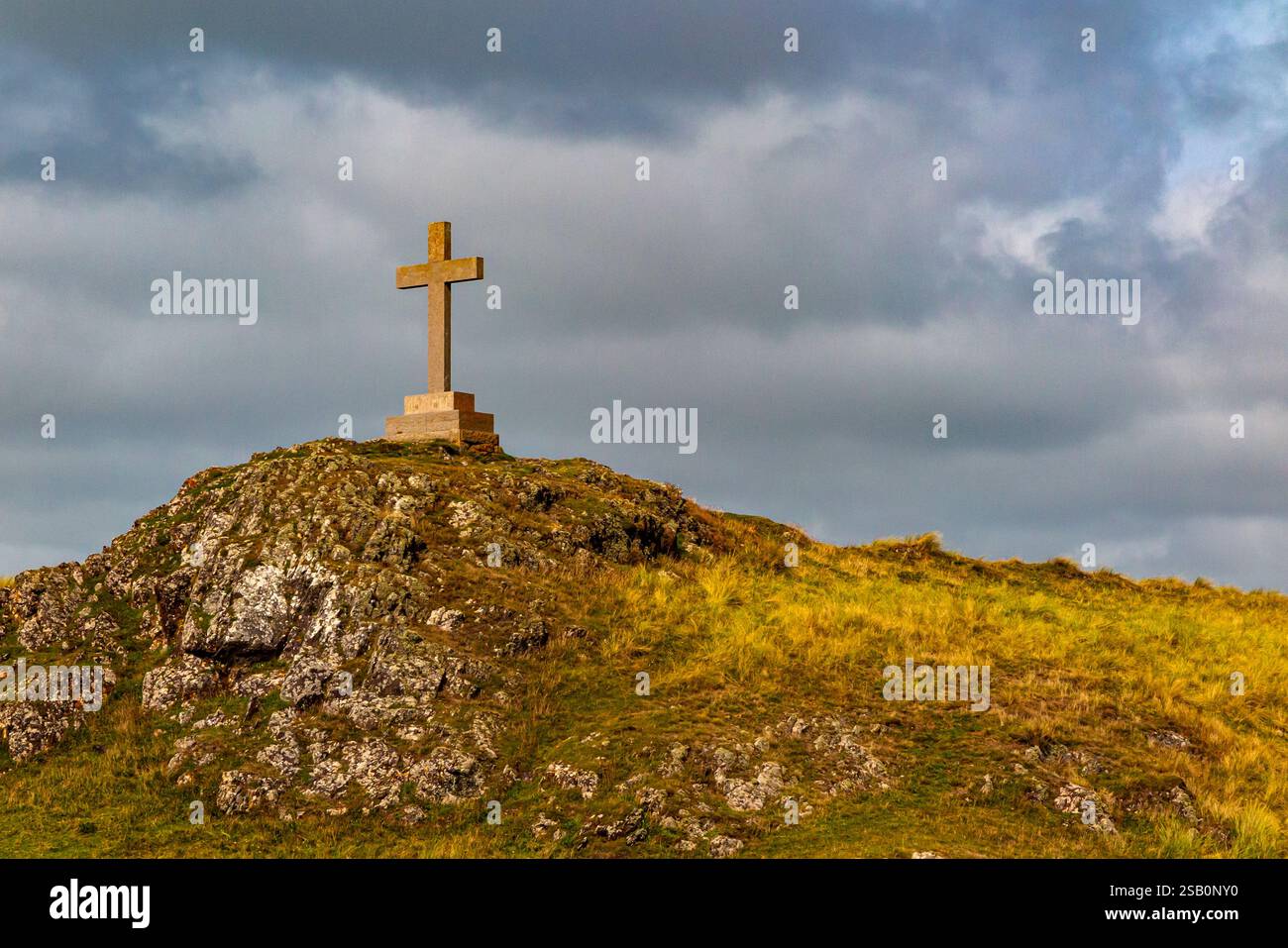 Hügelige Landschaft mit Kreuz auf Ynys Llanddwyn, einer kleinen Insel vor der Küste von Anglesey in Nordwales, Großbritannien. Stockfoto