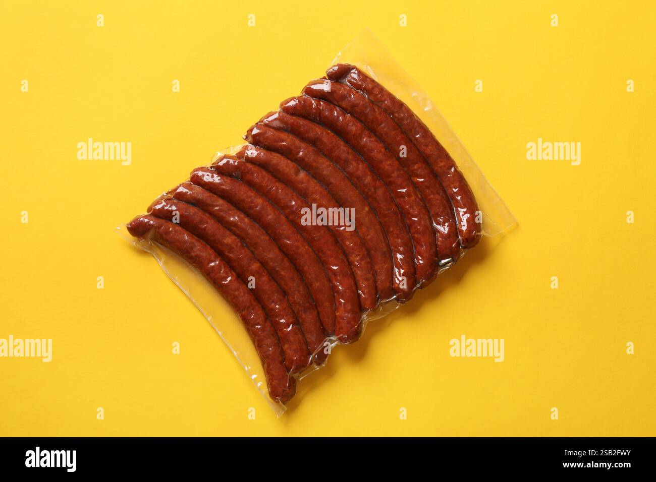 Packung geräucherte Würstchen auf gelbem Hintergrund, Draufsicht Stockfoto
