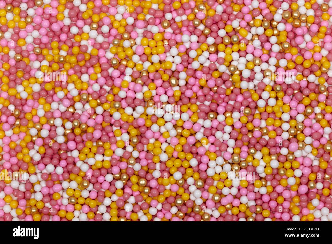 Farbenfroher Zucker-Sprinkles-Hintergrund mit rosa, weißen, gelben und goldenen Süßigkeiten-Perlen – süße Süßwaren-Textur für Backen, Kuchen-Dekoration und Dess Stockfoto