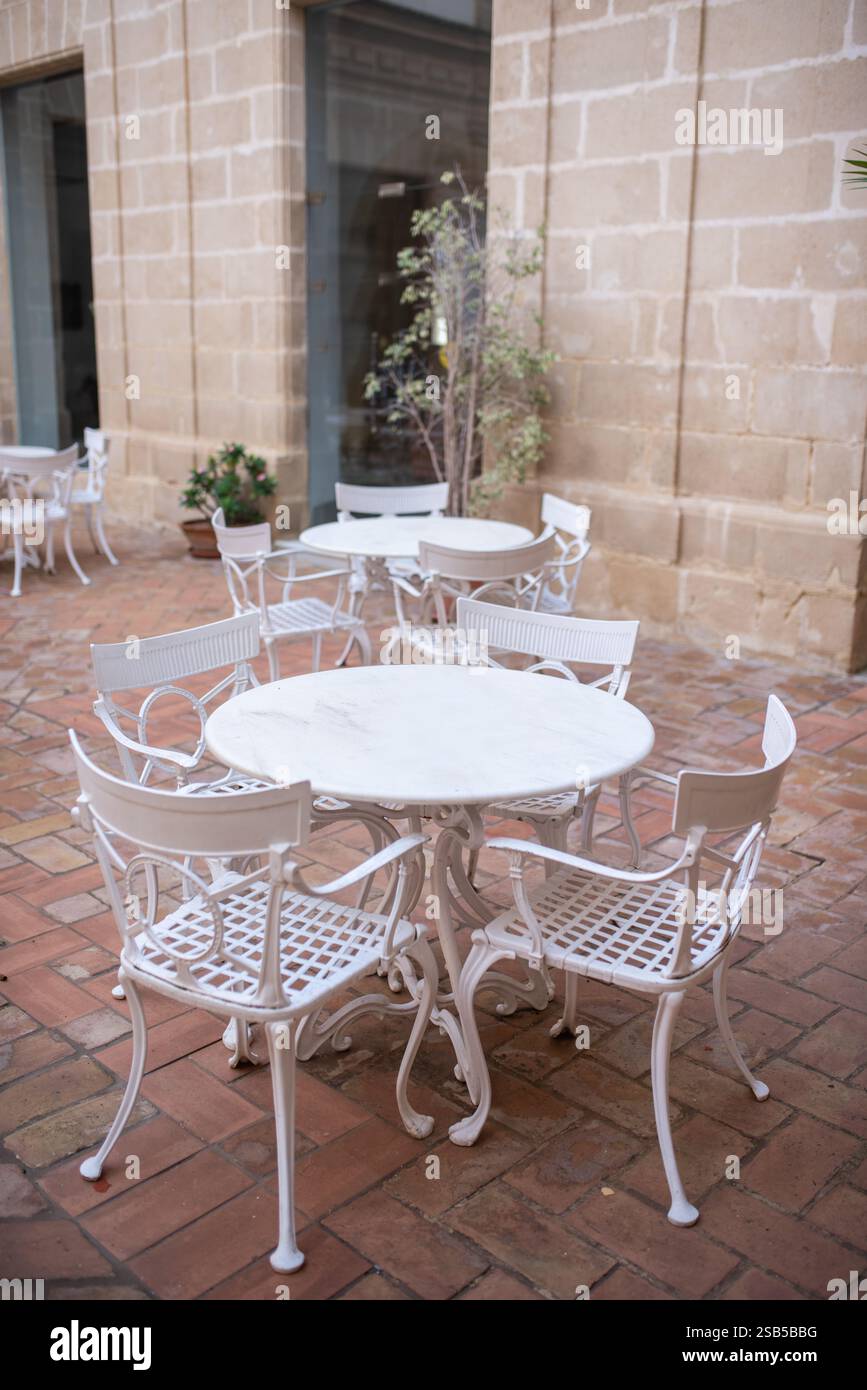 Weiße leere Metallstühle und -Tische im viktorianischen Stil im Café im Freien. Schmiedeeiserne Möbel, altmodische gemütliche Café-Terrasse, Restauranttische warten auf Sie Stockfoto