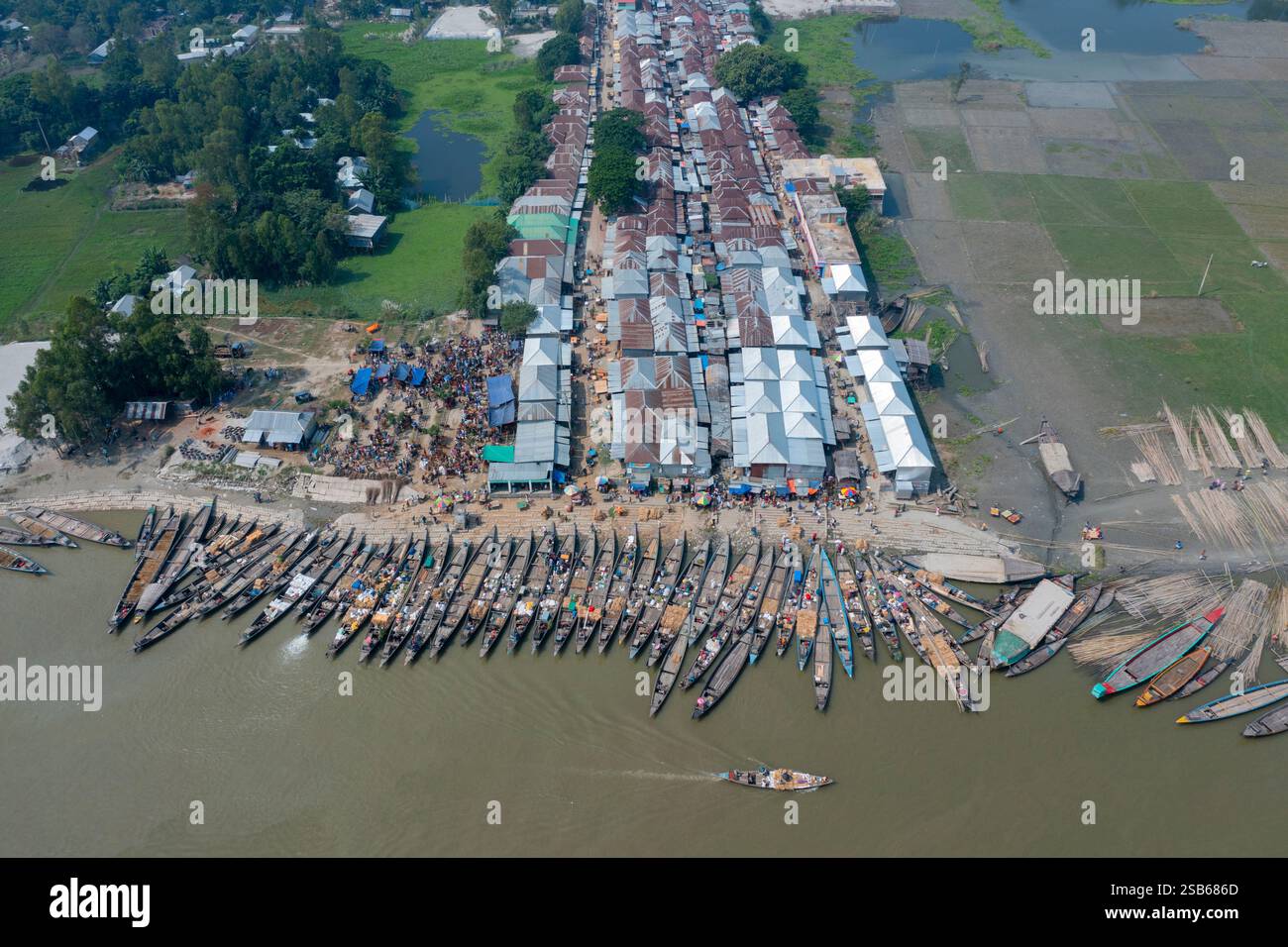Blick aus der Vogelperspektive auf den belebten Basar am Flussufer Nakalia mit einer Flotte von Booten, die am Ufer des Brahmaputra River in Bera, Pabna, ankern. Stockfoto Blick aus der Vogelperspektive auf den belebten Basar am Flussufer Nakalia mit einer Flotte von Booten, die am Ufer des Brahmaputra River in Bera, Pabna, ankern. Stockfoto
