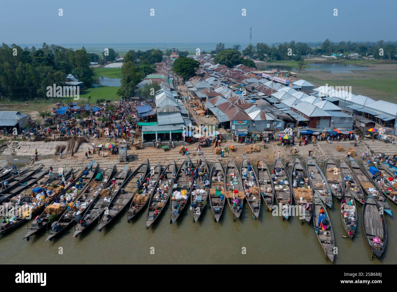 Blick aus der Vogelperspektive auf den belebten Basar am Flussufer Nakalia mit einer Flotte von Booten, die am Ufer des Brahmaputra River in Bera, Pabna, ankern. Stockfoto Blick aus der Vogelperspektive auf den belebten Basar am Flussufer Nakalia mit einer Flotte von Booten, die am Ufer des Brahmaputra River in Bera, Pabna, ankern. Stockfoto