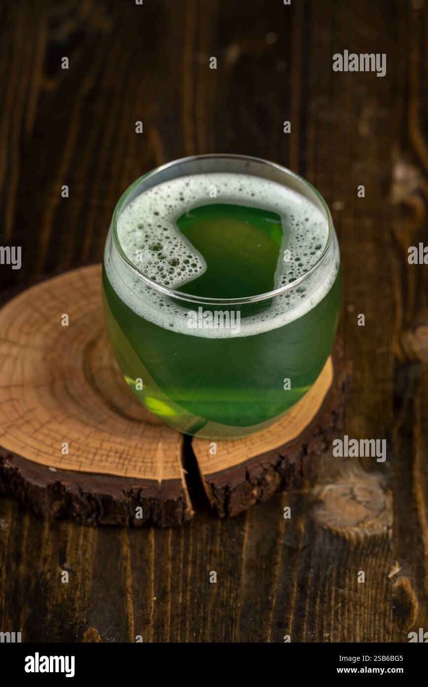 Ein grünes kohlensäurehaltiges Getränk aus Kräutern mit weißem Schaum, in ein Glas ein natürliches Getränk mit Gas gegossen Stockfoto