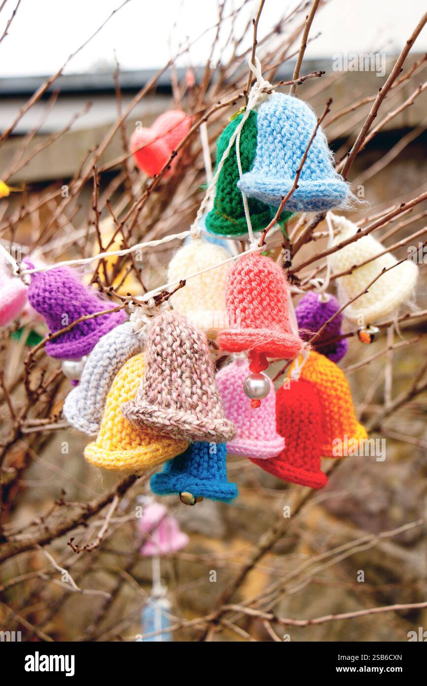 Farbenfrohe gestrickte Häkelschmuck, die an Ästen hängen, schaffen eine festliche und handgefertigte Ausstellung im Freien im Beadnell Hafen northumberland uk Stockfoto