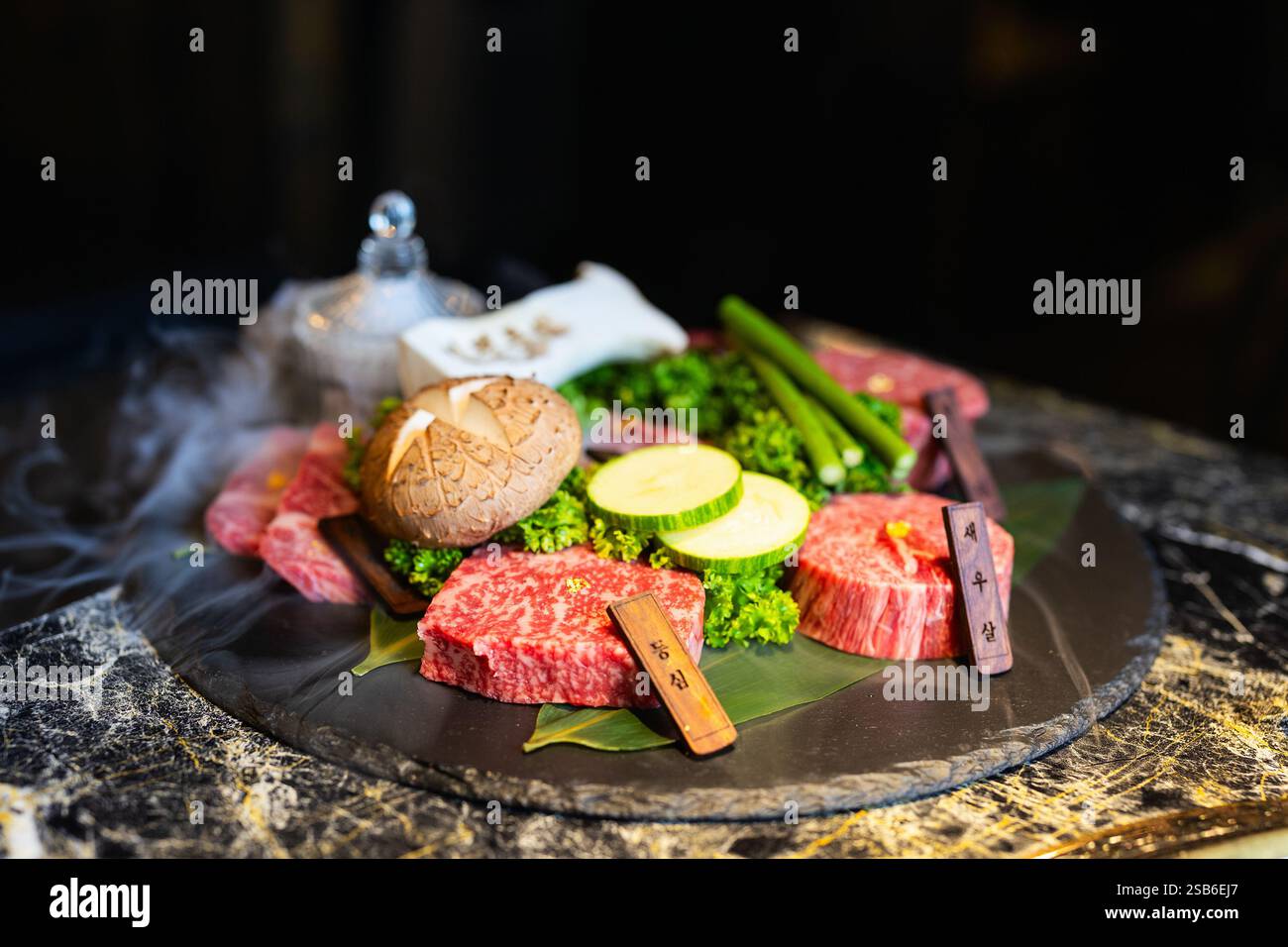 Eine wunderschön präsentierte koreanische Grillplatte mit marmoriertem Rindfleisch, frischem Gemüse und Pilzen Stockfoto
