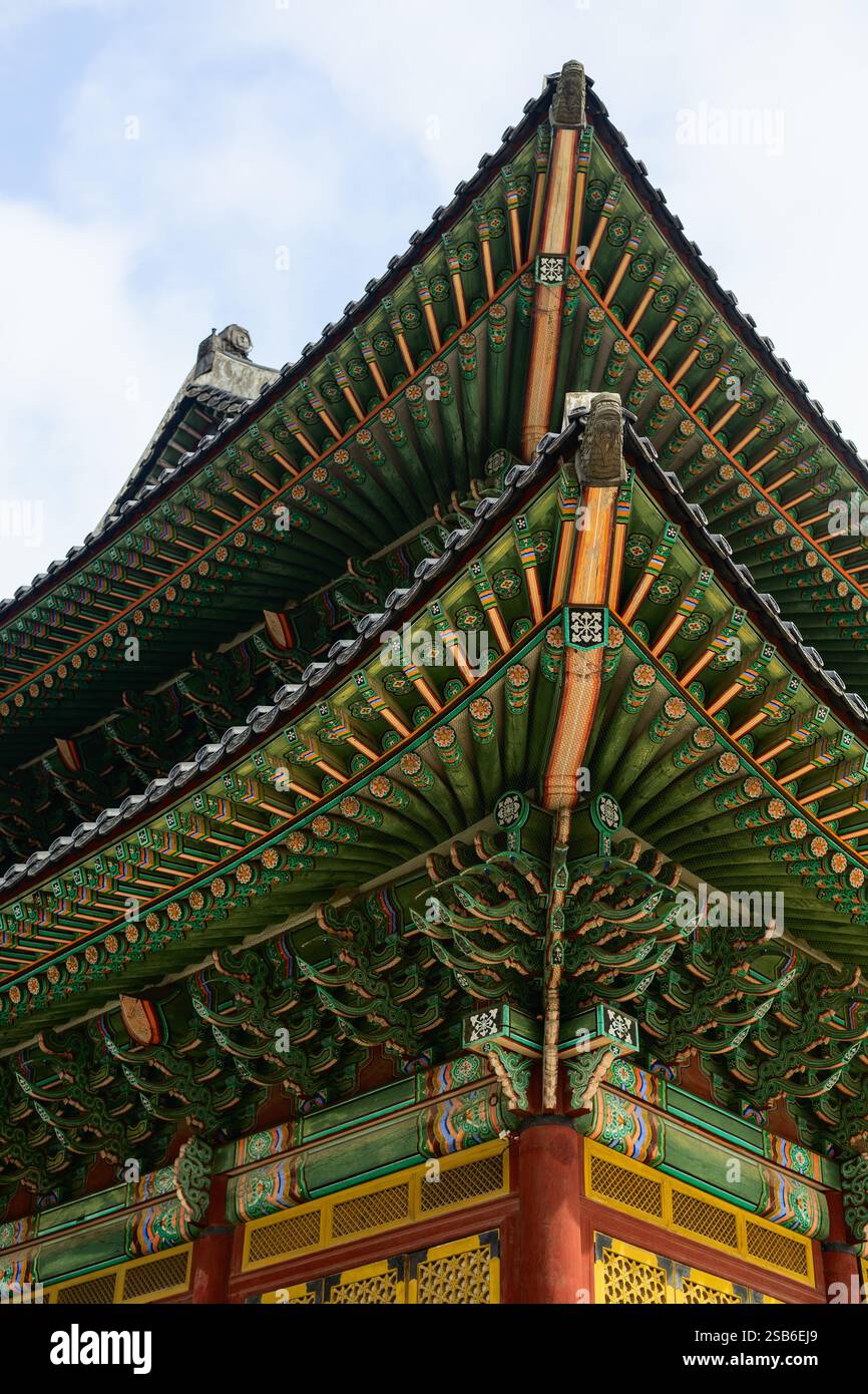 Detaillierter Blick auf die kunstvoll verzierte Dachkonstruktion eines traditionellen koreanischen Tempels mit komplizierten Holzbalken und bunten gemalten Mustern Stockfoto