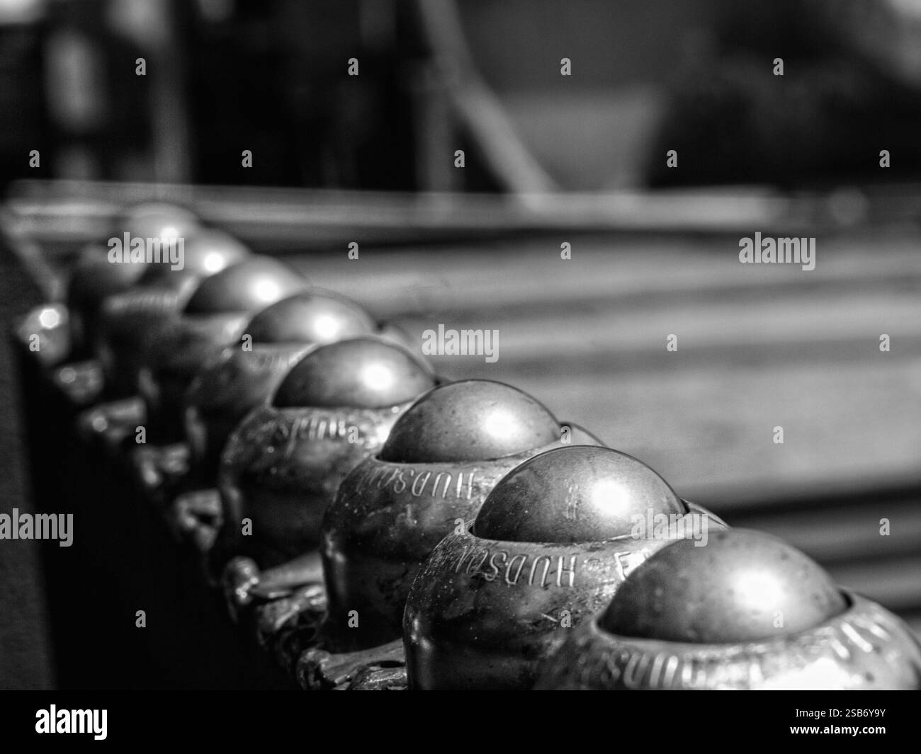 Ein Schwarzweiß-Foto von nacheinander gefüllten metallischen Förderrollen, die ihre glatten, abgenutzten Oberflächen und das mechanische Design hervorheben. Stockfoto