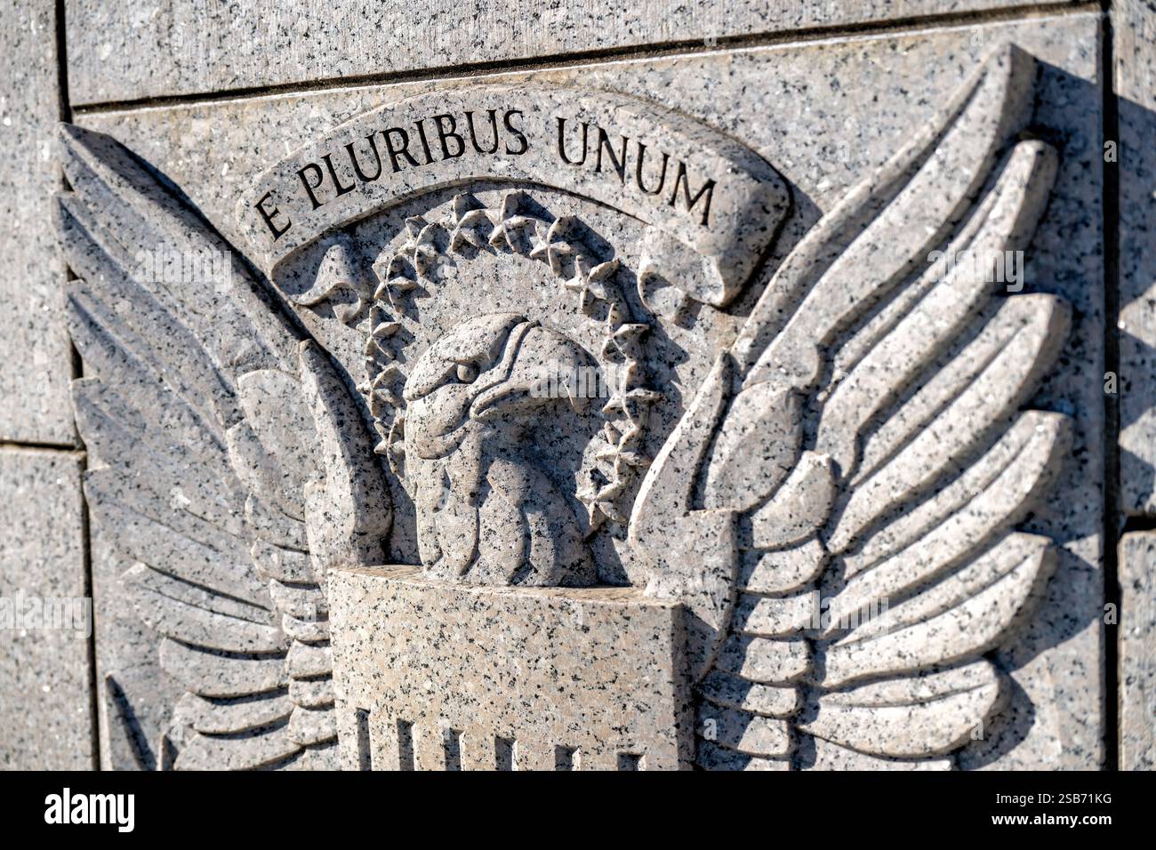 WASHINGTON DC – Ein Basreliefschild mit Adler, Pfeilen und Olivenzweigen ist in die Granitblöcke am östlichen Eingang des National World war II Memorial gemeißelt. Das skulpturale Detail spiegelt die traditionelle amerikanische Militärsymbolik wider. Das geschnitzte Emblem markiert einen der Haupteingänge der National Mall. Stockfoto