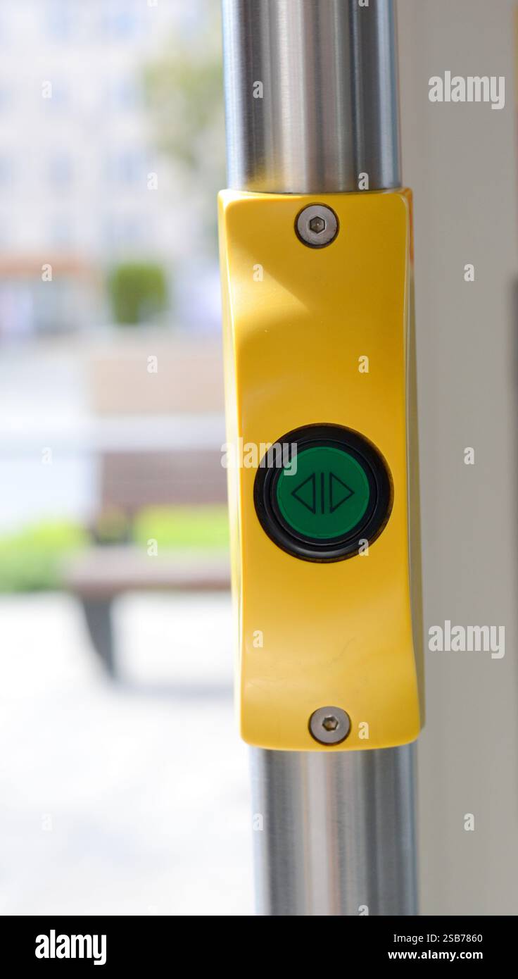 Gelbe und grüne Taste „Tür öffnen“ in einer Straßenbahn, die modernes Design und Funktionalität eines städtischen öffentlichen Verkehrssystems unterstreicht Stockfoto