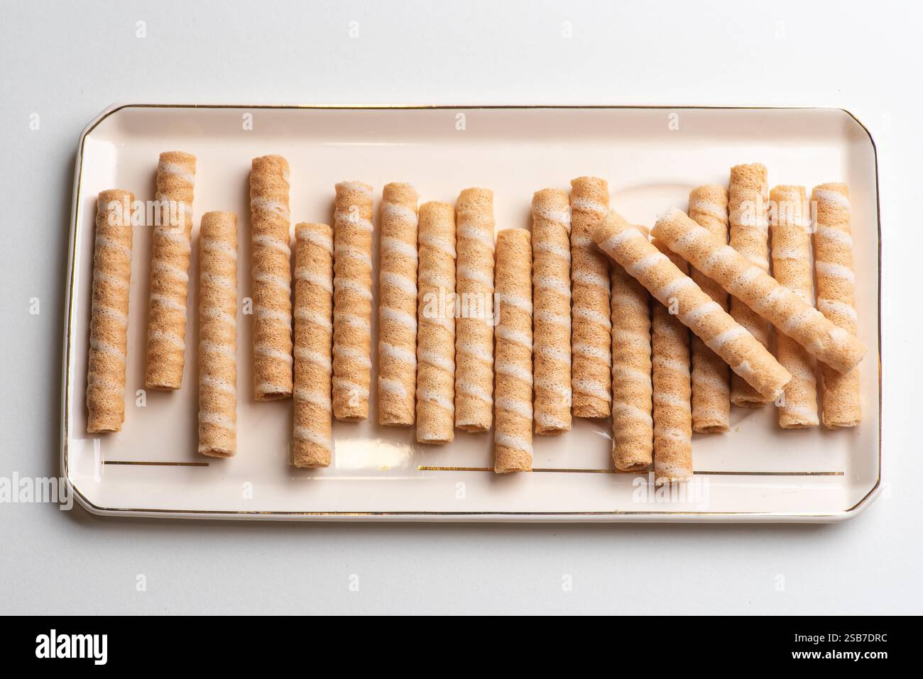 Eine schöne Präsentation knuspriger, gerollter Wafer-Sticks, die elegant auf einem Tablett angeordnet sind, ideal für festliche Versammlungen und Festlichkeiten. Stockfoto