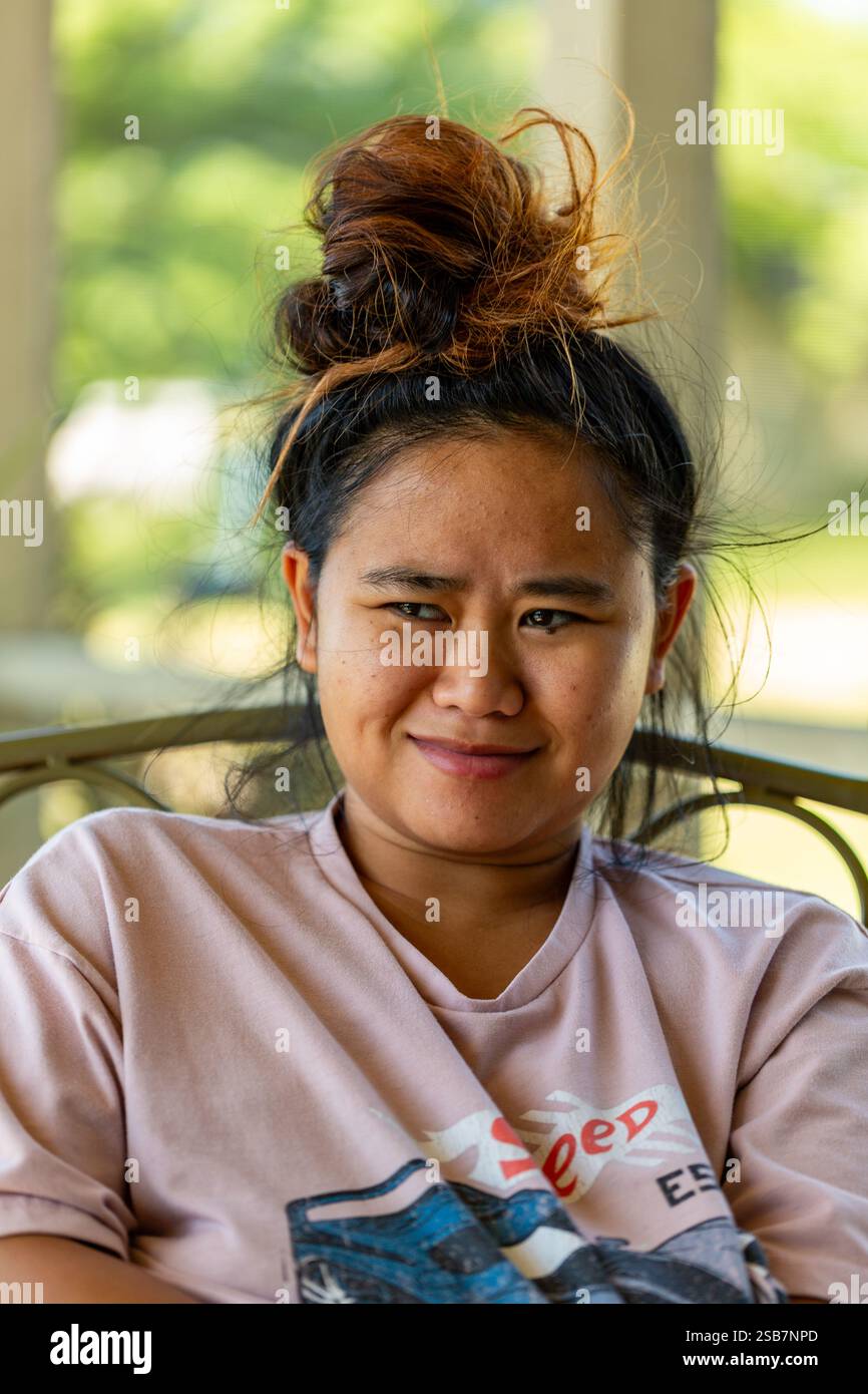 Ein lächelndes asiatisches Mädchen mit einer unordentlichen Brötchenfrisur. Stockfoto