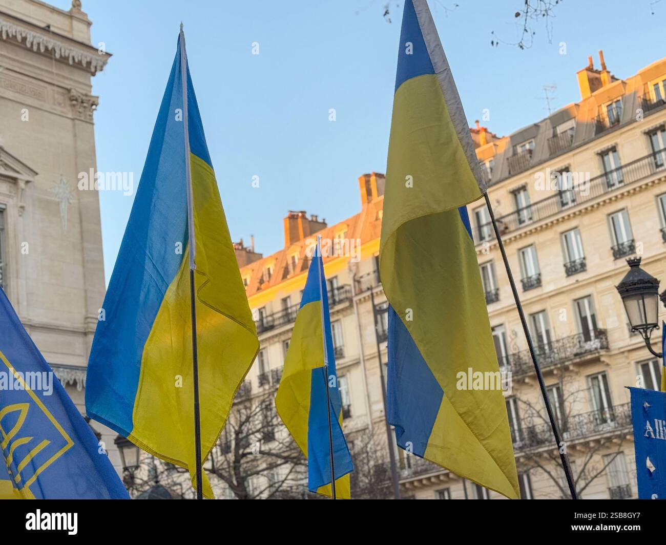 Die Fahnen wehen stolz auf die Ukraine auf einem pulsierenden Pariser Platz bei Tageslicht Stockfoto