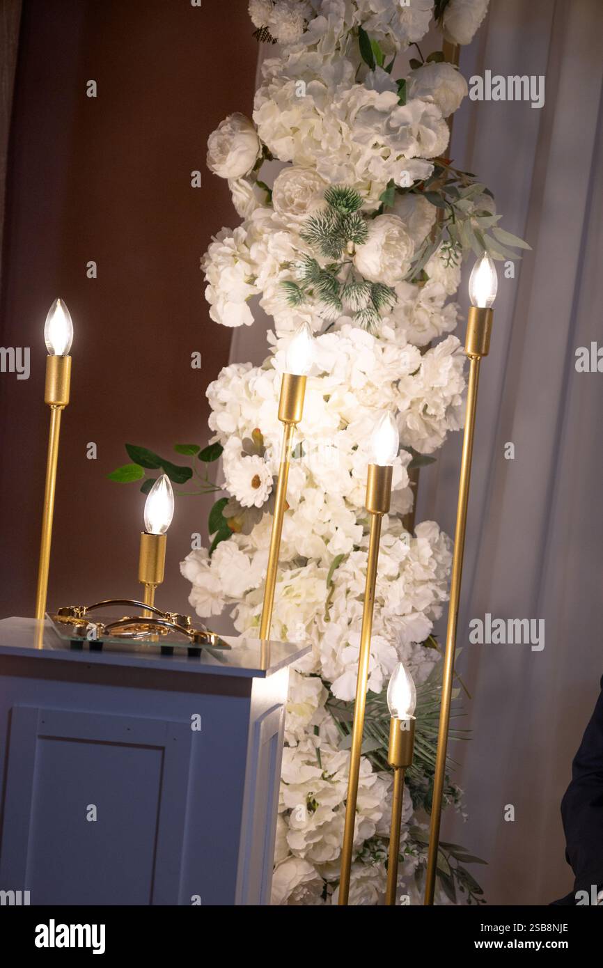 Kerzenlicht in der Nacht. Hochzeitsblume mit weißer Orchidee und goldener Kerze Stockfoto