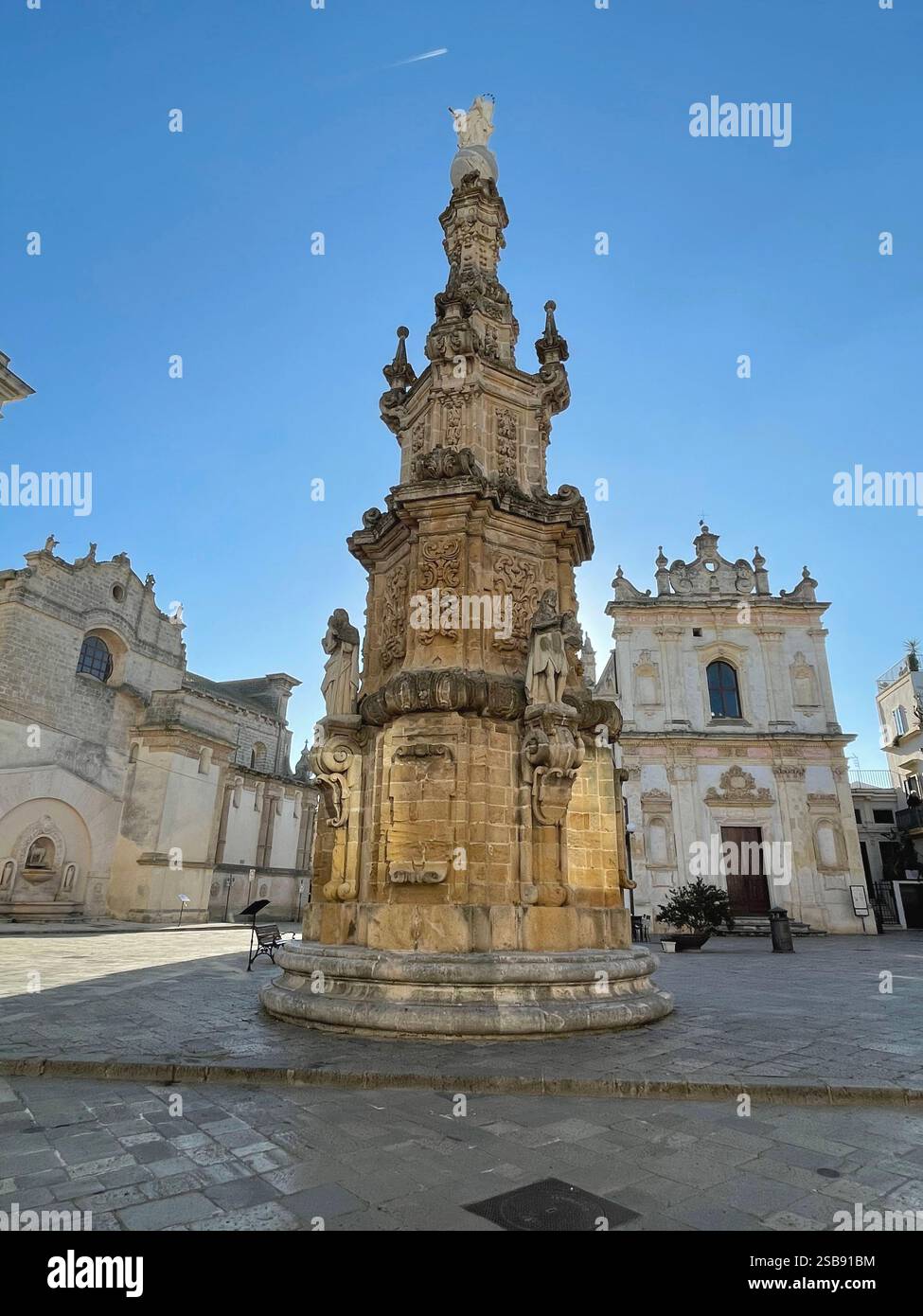 Nardò, Italien. Die Säule aus dem 18. Jahrhundert (Guglia dell'Immacolata) und die Chiesa di San Trifone auf der Piazza Salandra. - Smartphone-aufgenommenes Stockfoto