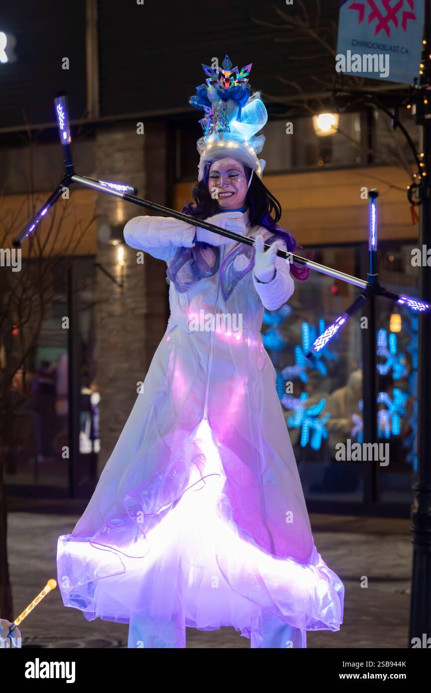 Eine Künstlerin auf Stelzen, gekleidet in einem festlichen Winterkostüm beim Calgary Chinook Blast Festival, die einen beleuchteten Schlagstock umwirbelt. Alberta Kanada. Stockfoto