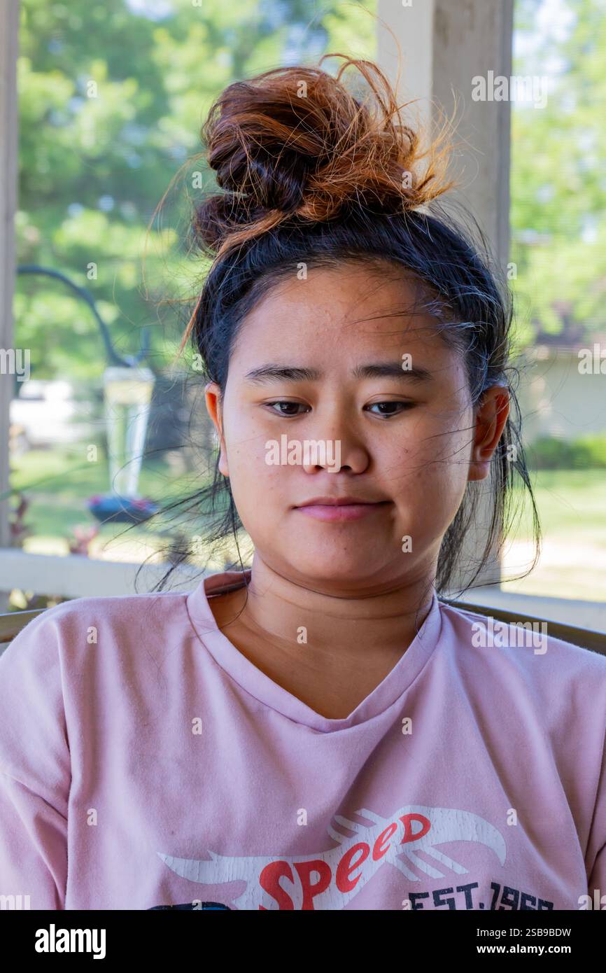 Ein lächelndes asiatisches Mädchen mit einer unordentlichen Brötchenfrisur. Stockfoto