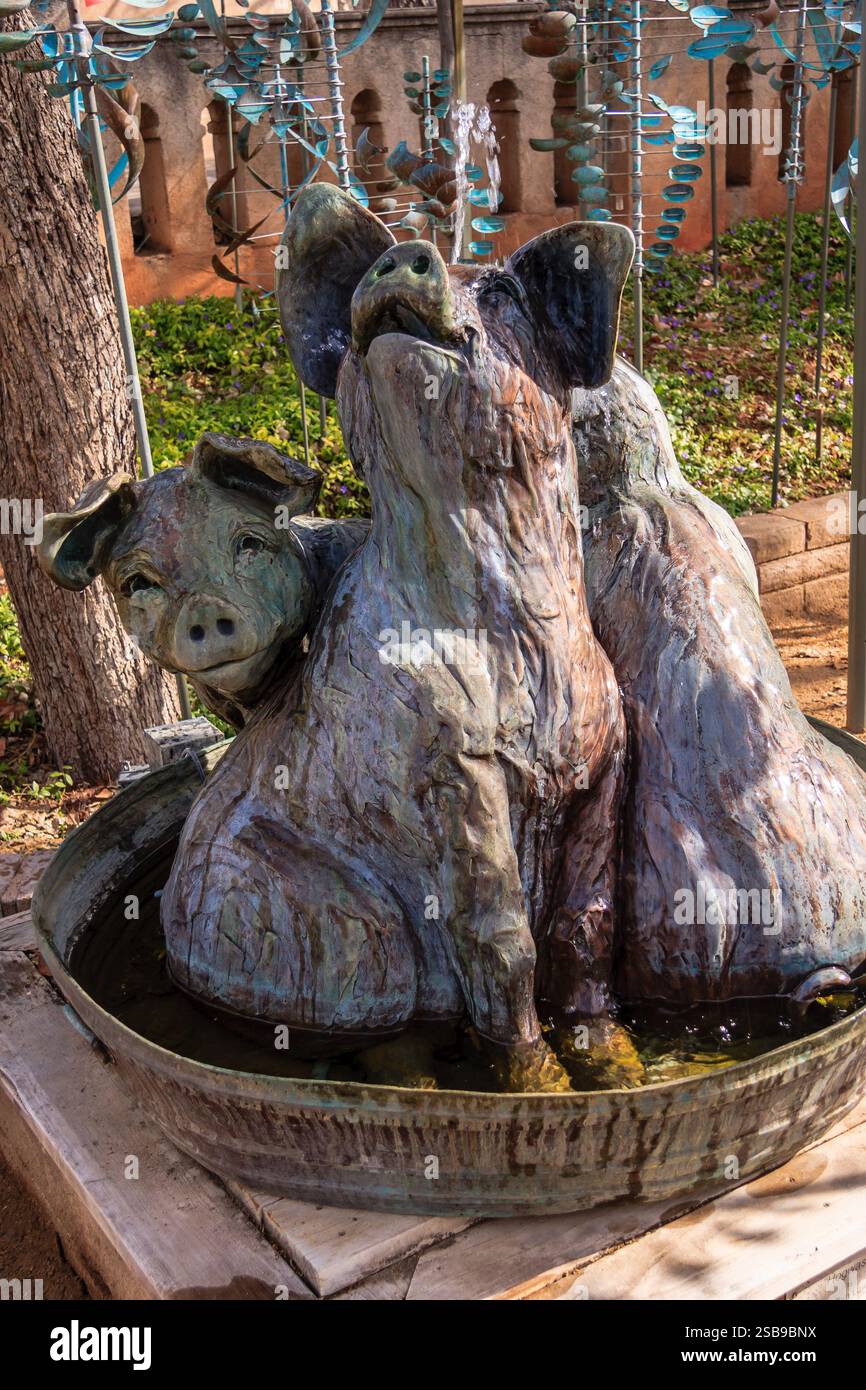 Eine Skulptur von drei Schweinen sitzt in einem kleinen Teich. Die Skulptur ist aus Metall und hat ein verspieltes, skurriles Gefühl Stockfoto