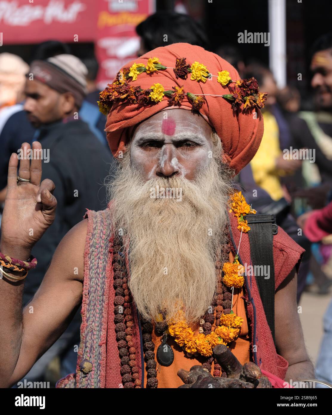 Eine Nahaufnahme eines heiligen Mannes mit gemaltem Gesicht und Blumengirlanden im Maha Kumbh Mela in Prayagraj, Indien. Stockfoto