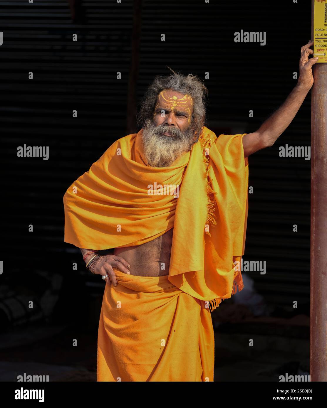 Prägnantes Porträt eines Ältesten in lebendiger orangener traditioneller Kleidung, das kulturellen Reichtum und würde ausstrahlt. Stockfoto