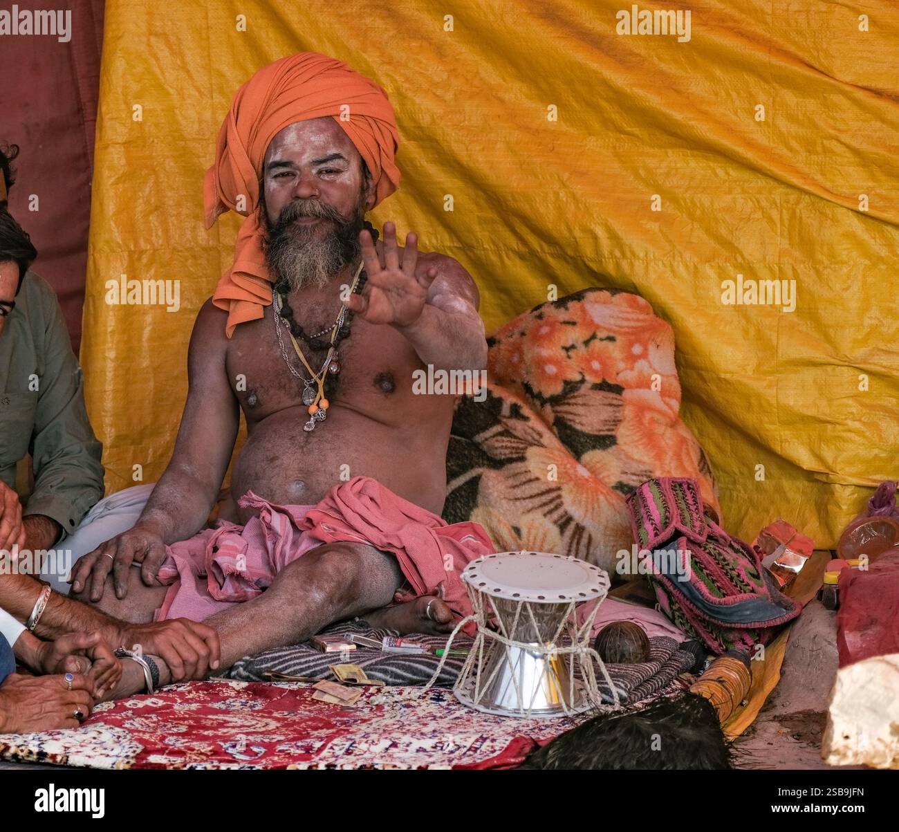 Eine heitere Naga Sadhu, die während des Kumbh Mela Festivals in seinem Zelt sitzt. Stockfoto