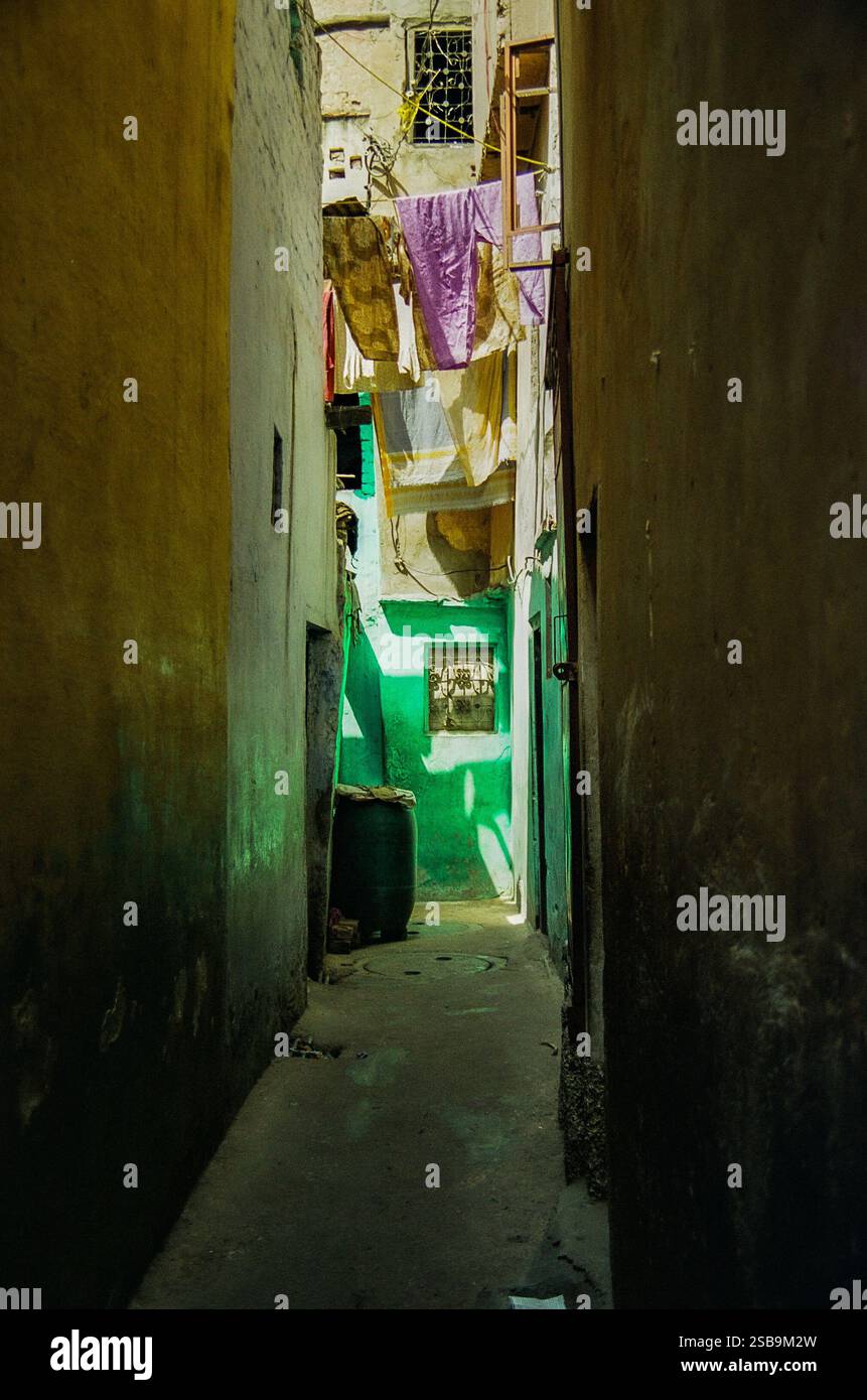 In einer engen Gasse in Neu-Delhi, Indien, hängen bunte Wäschereilinien zwischen Gebäuden. Stockfoto In einer engen Gasse in Neu-Delhi, Indien, hängen bunte Wäschereilinien zwischen Gebäuden. Stockfoto