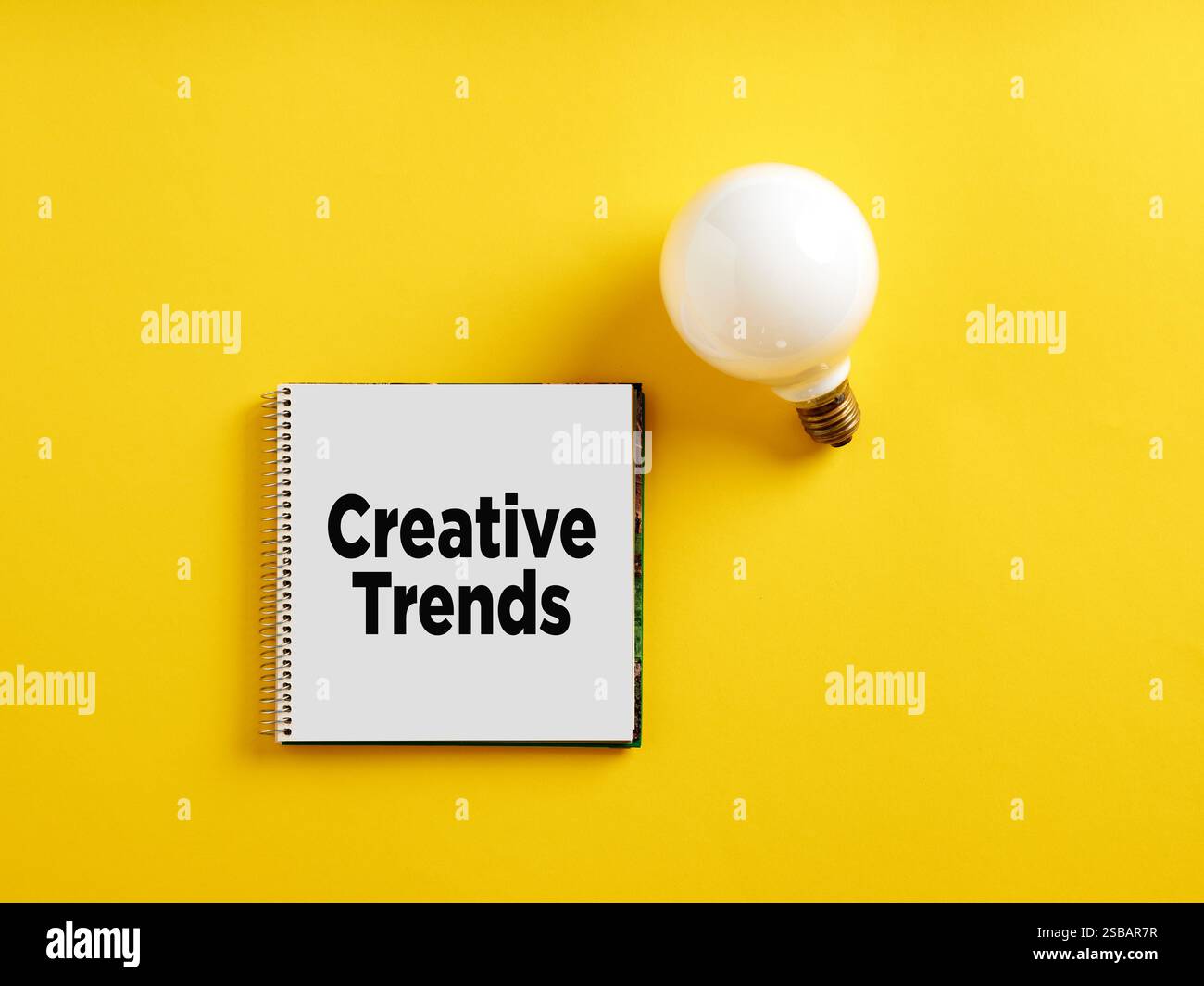 Die Botschaft kreative Trends auf Notizblock mit Glühbirne. Konzept kreativer Branchentrends. Stockfoto