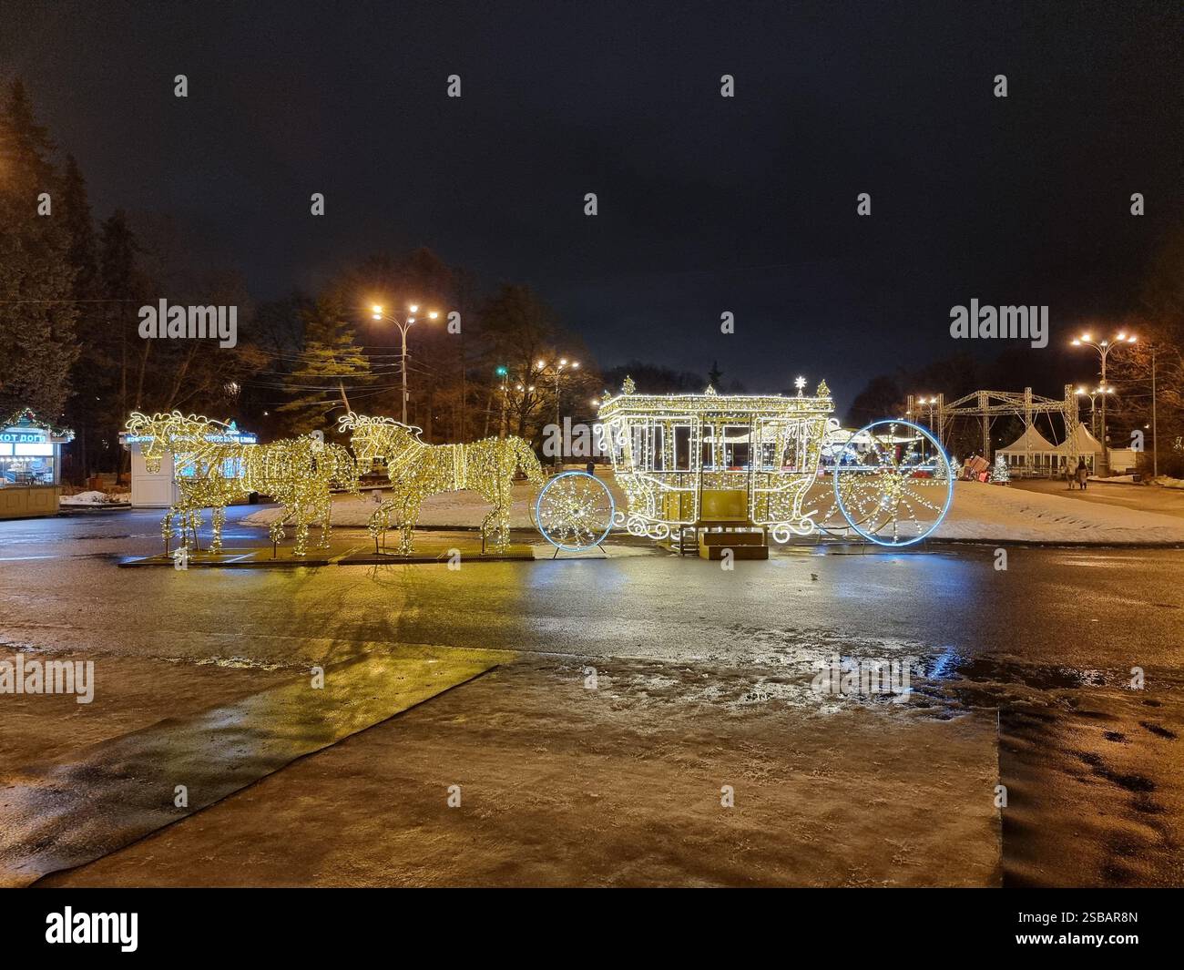 Glänzende Lichtskulptur einer Pferdekutsche mit Pferden im Dunkeln in einem Park - Smartphone-aufgenommenes Stockfoto