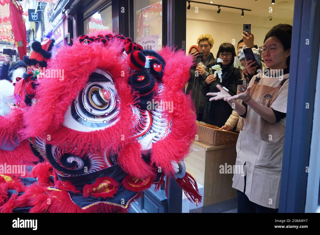 Ein Mitarbeiter der Mrs Bakery in Chinatown in London interagiert mit einem Löwentänzer während Mondneujahrsfeiern, auch bekannt als Frühlingsfest oder Chinesisches Neujahr. Bilddatum: Sonntag, 2. Februar 2025. Stockfoto